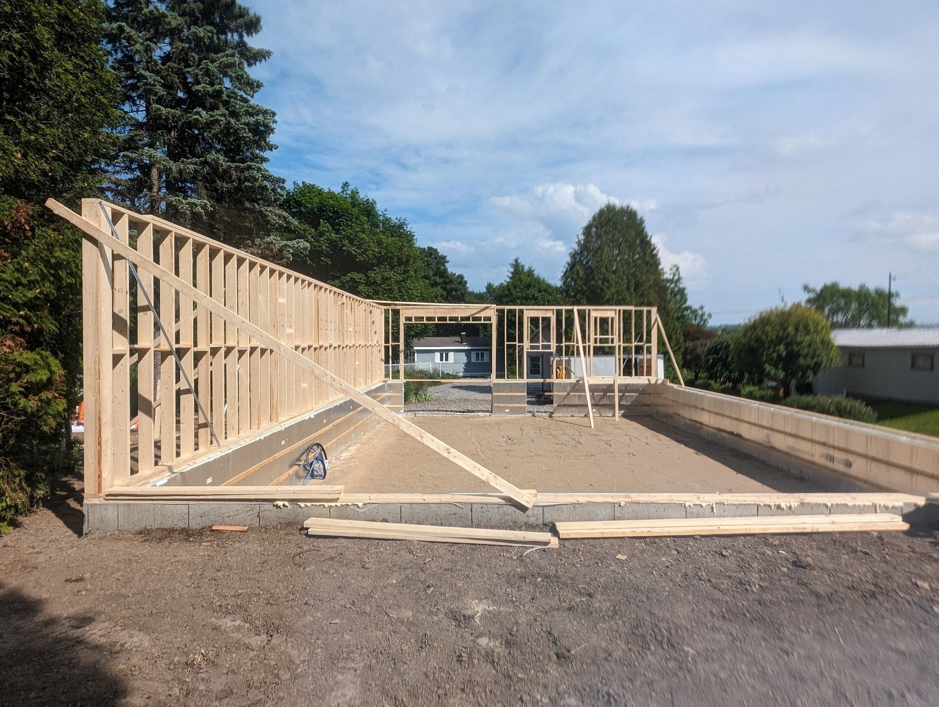 Une grande structure en bois est en cours de construction sur un chemin de terre.