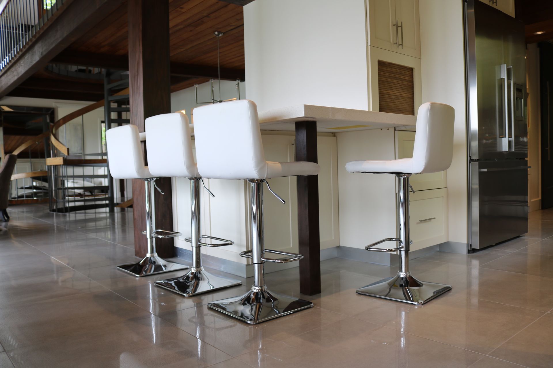 Une rangée de tabourets de bar blancs est placée à côté d'un comptoir dans une cuisine.