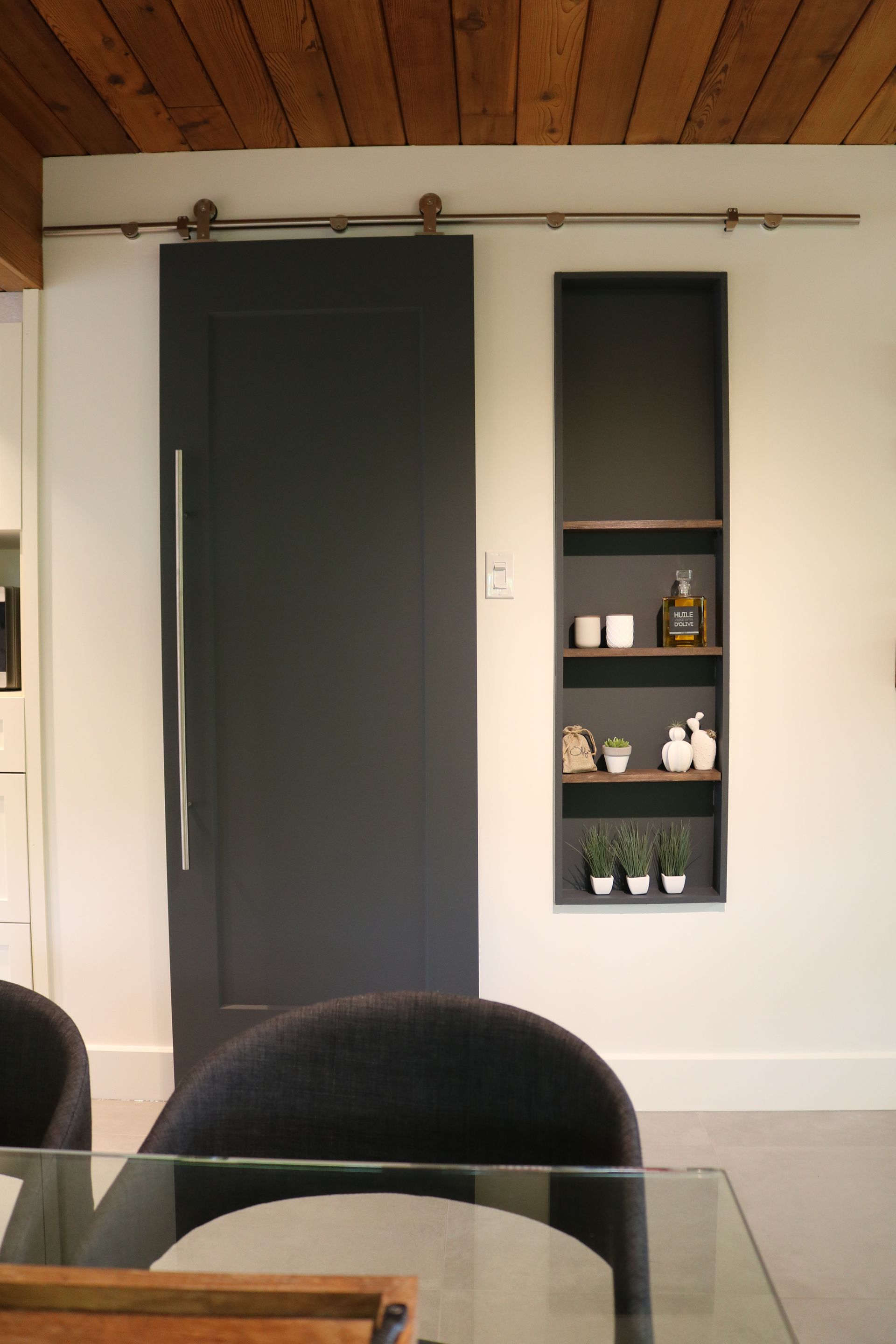 Une salle à manger avec une porte de grange coulissante et une table et des chaises en verre.