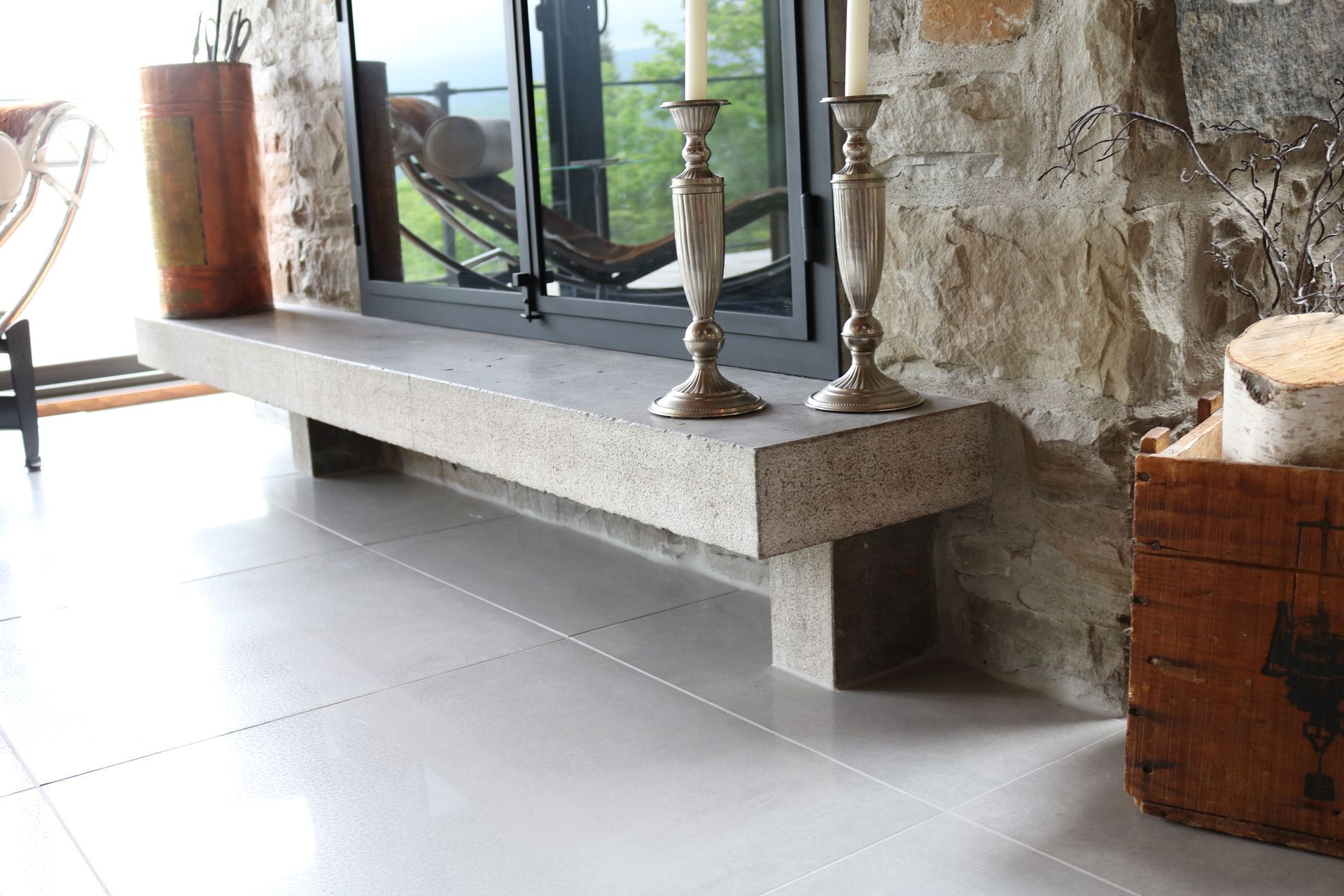 Une cheminée avec deux bougies dessus et un banc devant.