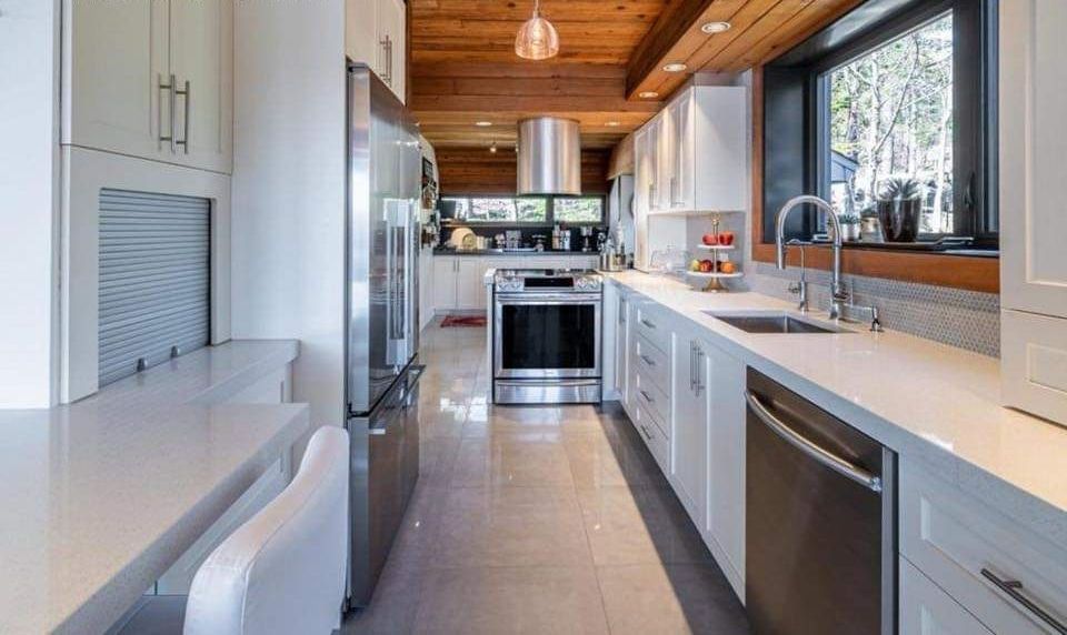 Une cuisine avec des armoires blanches et des appareils électroménagers en acier inoxydable.