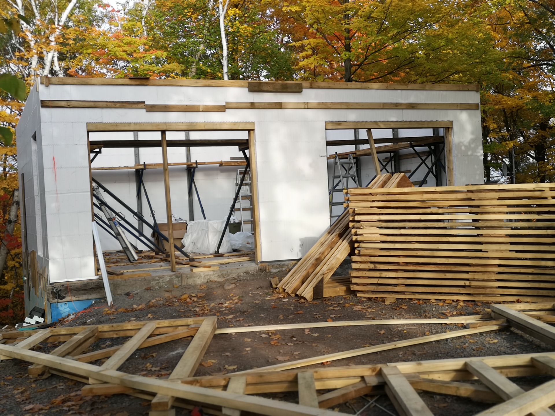 Un bâtiment en construction avec beaucoup de bois devant