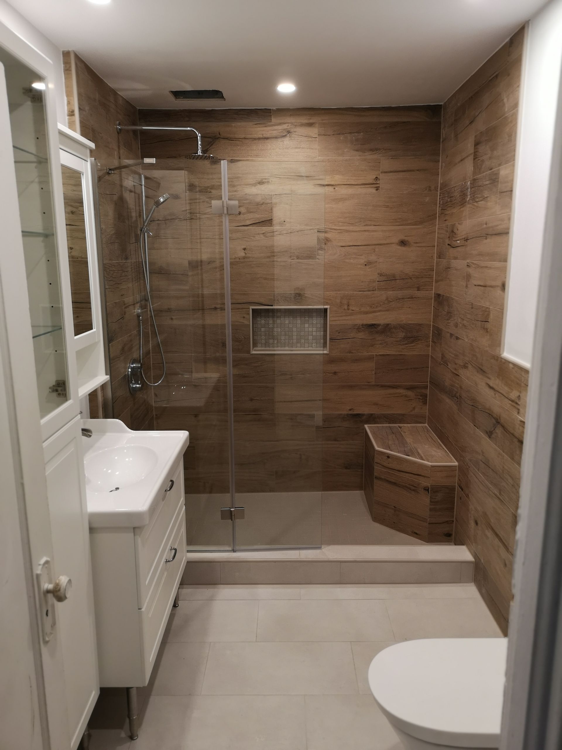 Une salle de bain avec douche à l'italienne, lavabo, WC et miroir.