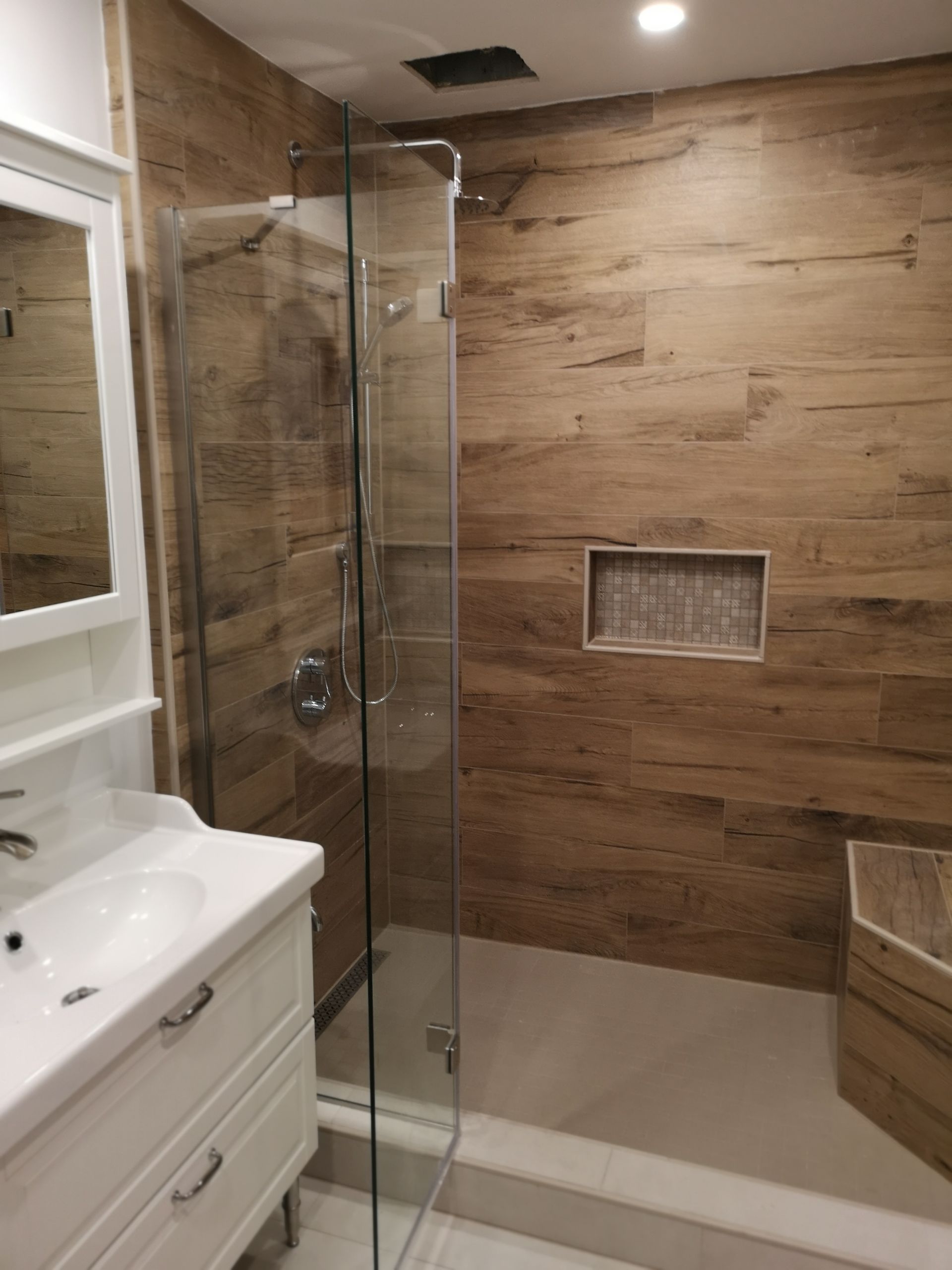 Une salle de bain avec baignoire, douche et porte de douche noire.