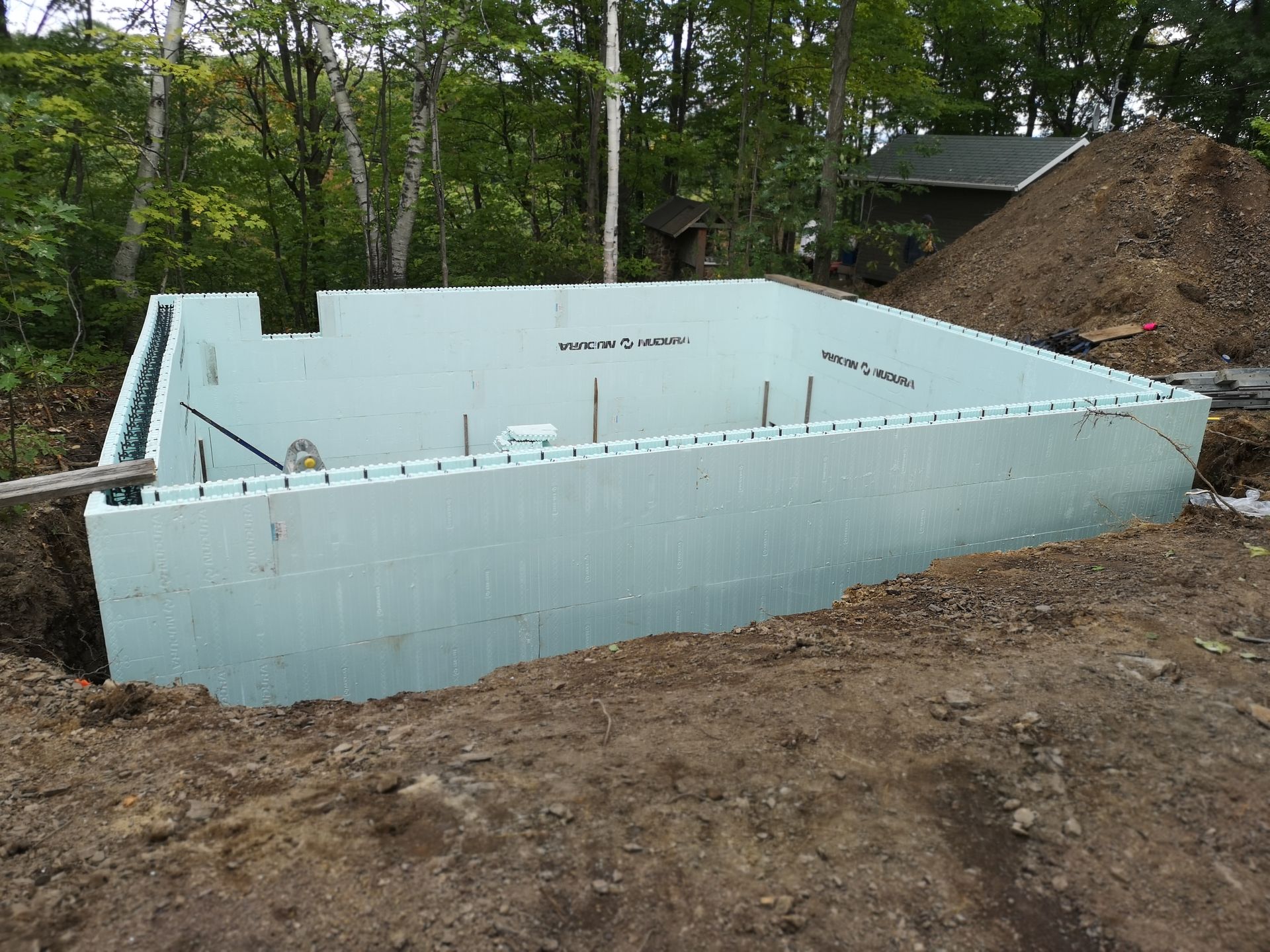 Une grande piscine est en cours de construction au milieu d'un champ de terre.