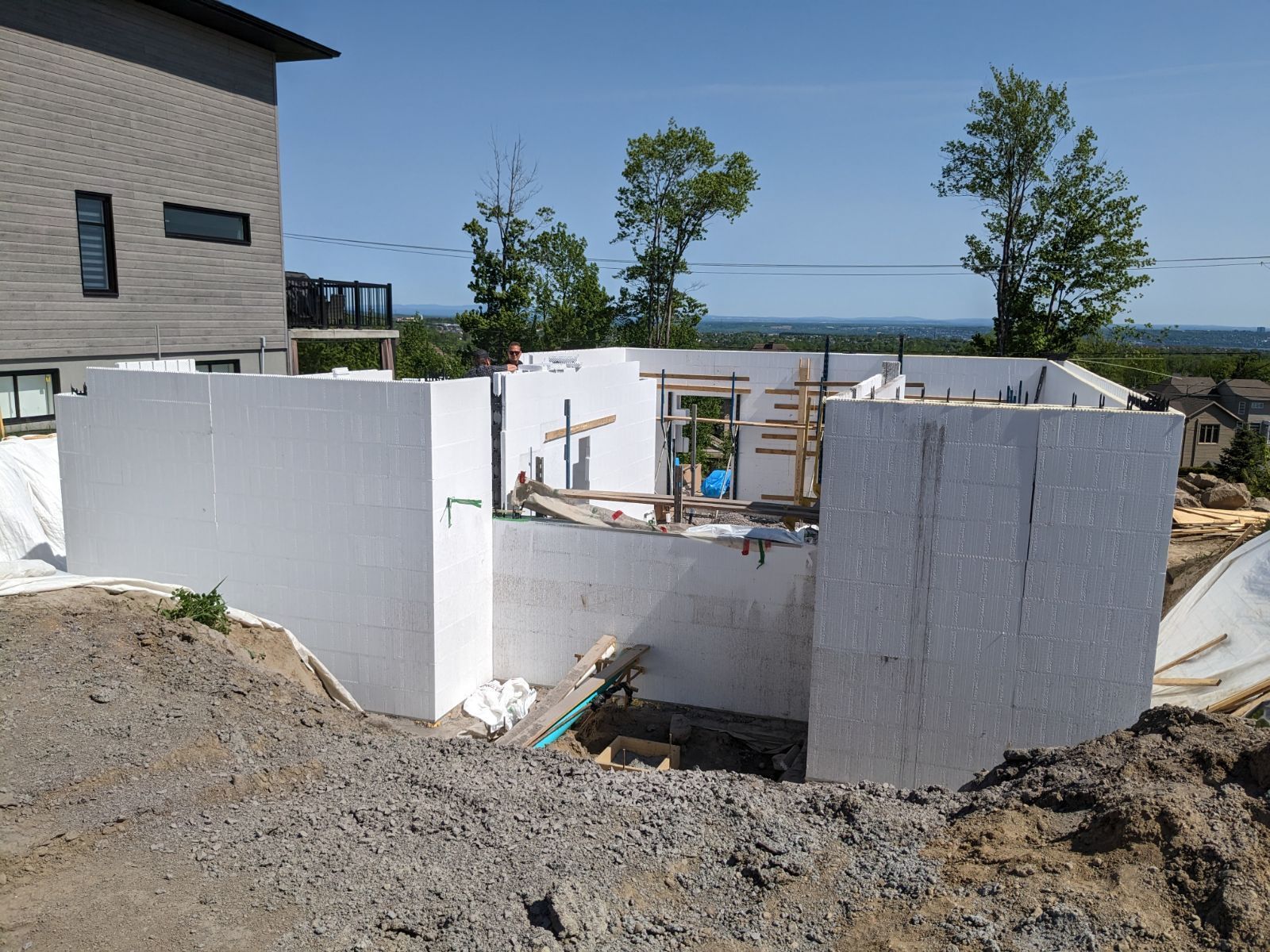 Un grand mur blanc est en construction devant une maison