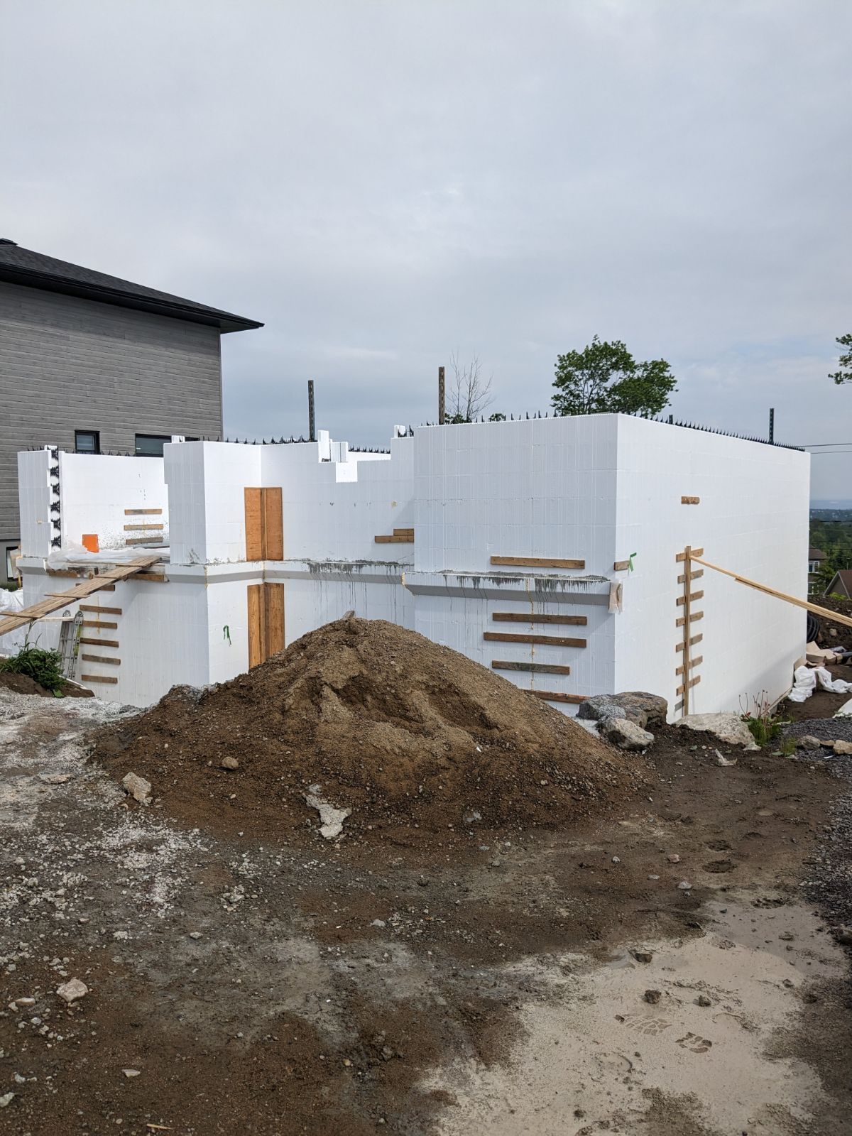 Un tas de terre se trouve devant un bâtiment en construction.