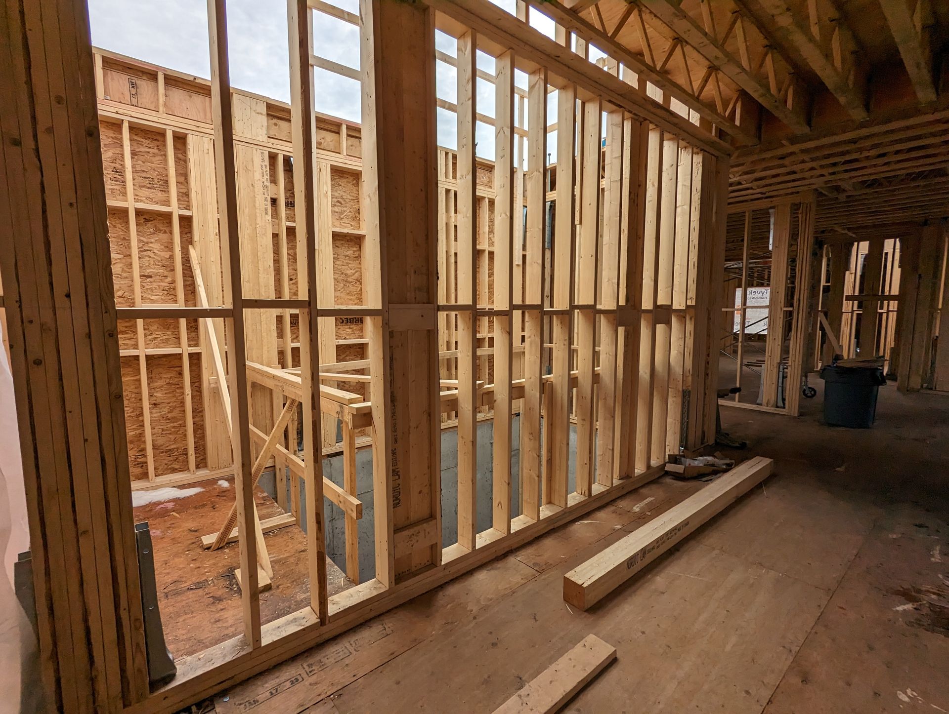 Une maison est en construction avec des ossatures en bois et beaucoup de fenêtres.