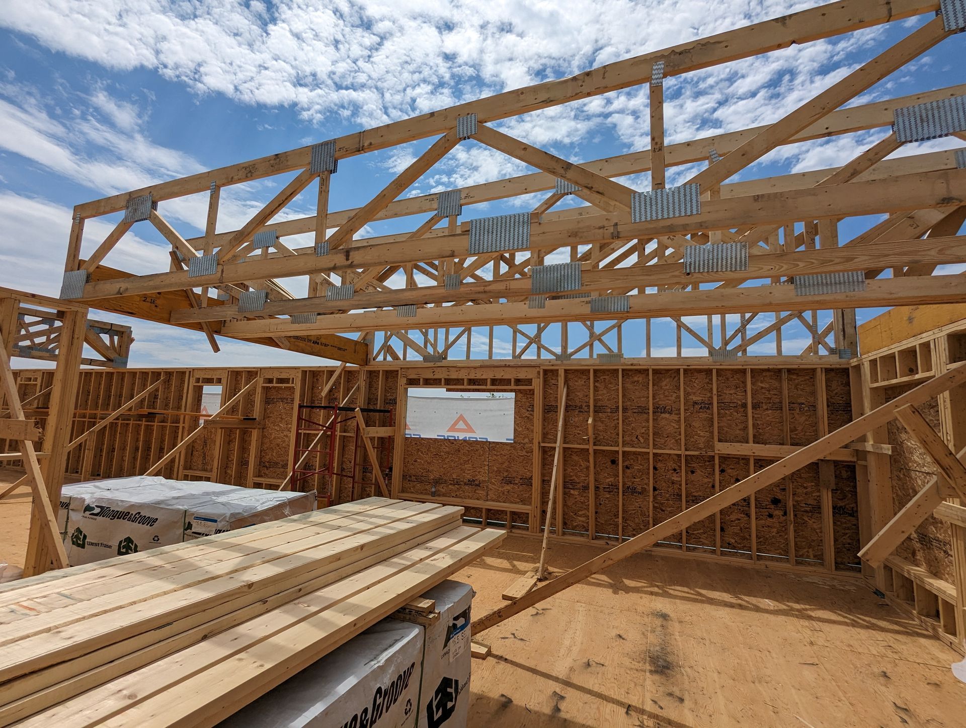 Une maison est en construction avec des poutres en bois et un ciel bleu en arrière-plan.