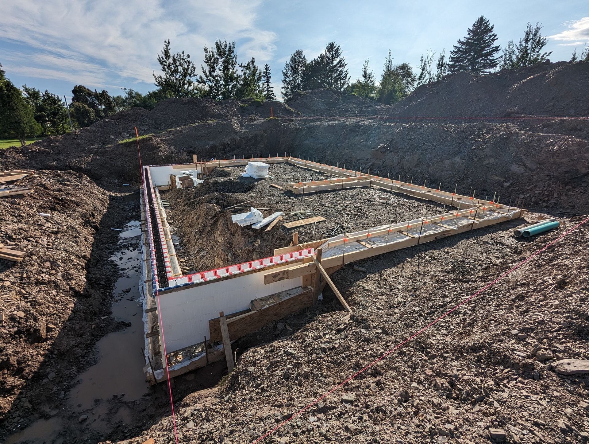 Un chantier de construction avec un gros tas de terre et des arbres en arrière-plan