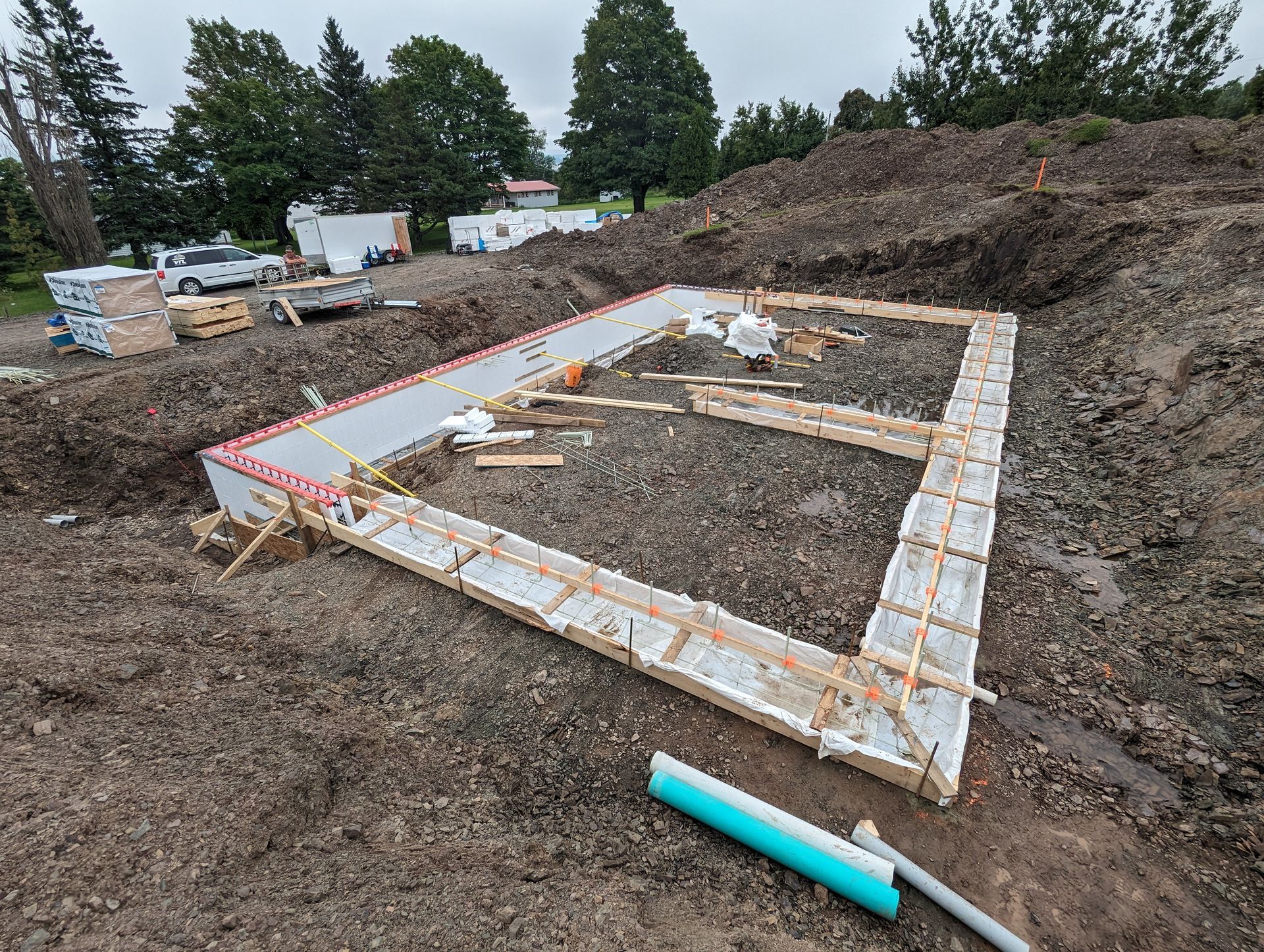 Une fondation en béton est en cours de construction dans un champ de terre.