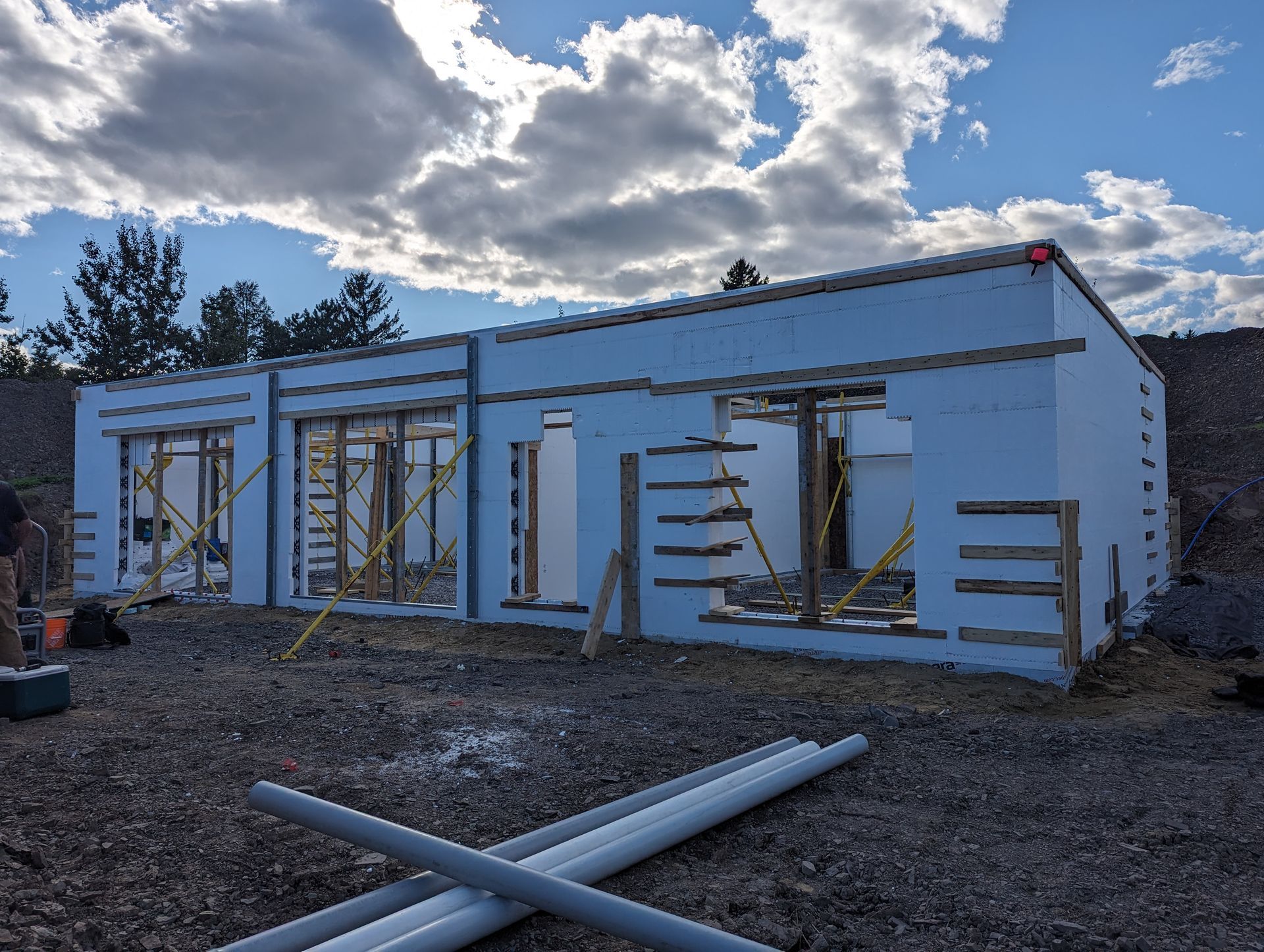 Un bâtiment est en construction avec beaucoup de tuyaux devant lui.