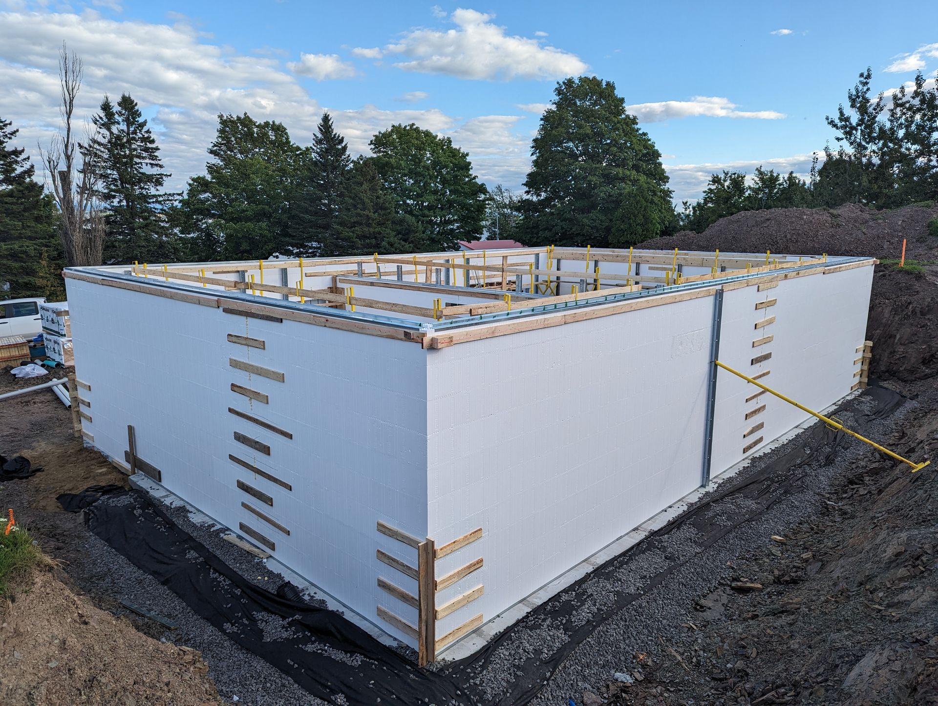 Un grand bâtiment est en cours de construction au sommet d'une colline de terre.