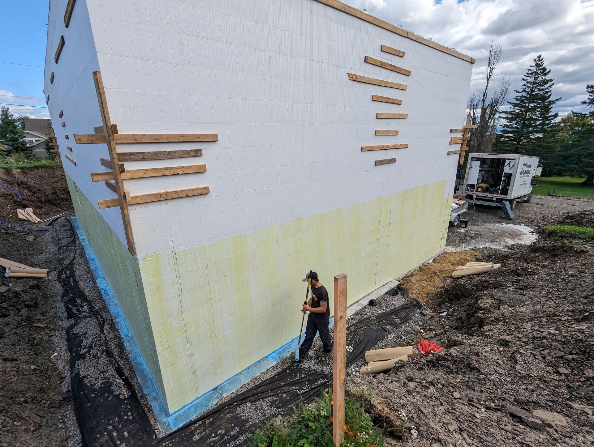 Un homme se tient devant un grand bâtiment en construction.