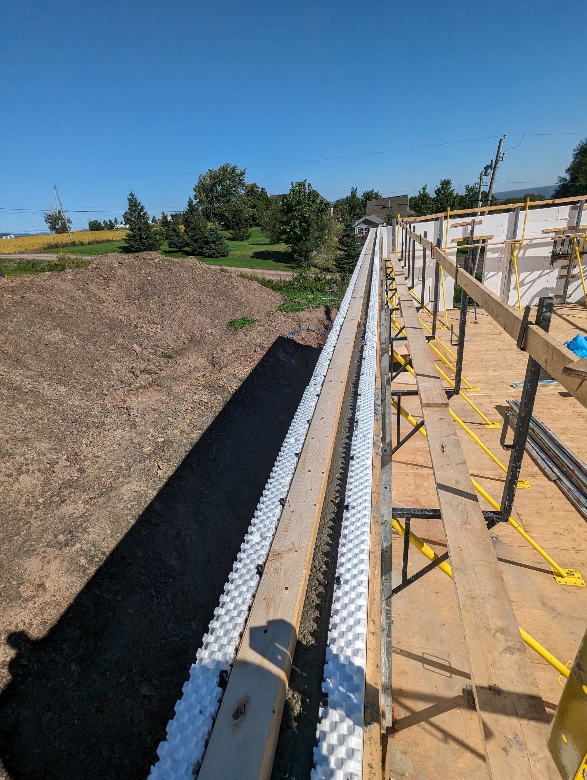 Une rangée d'échafaudages en bois posés sur un terrain en terre.