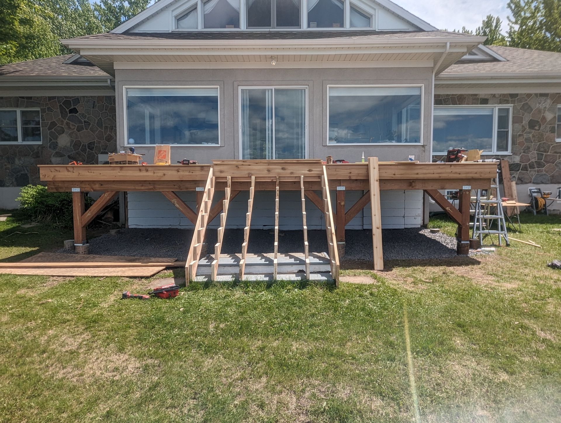 Une terrasse en bois est en cours de construction devant une maison.