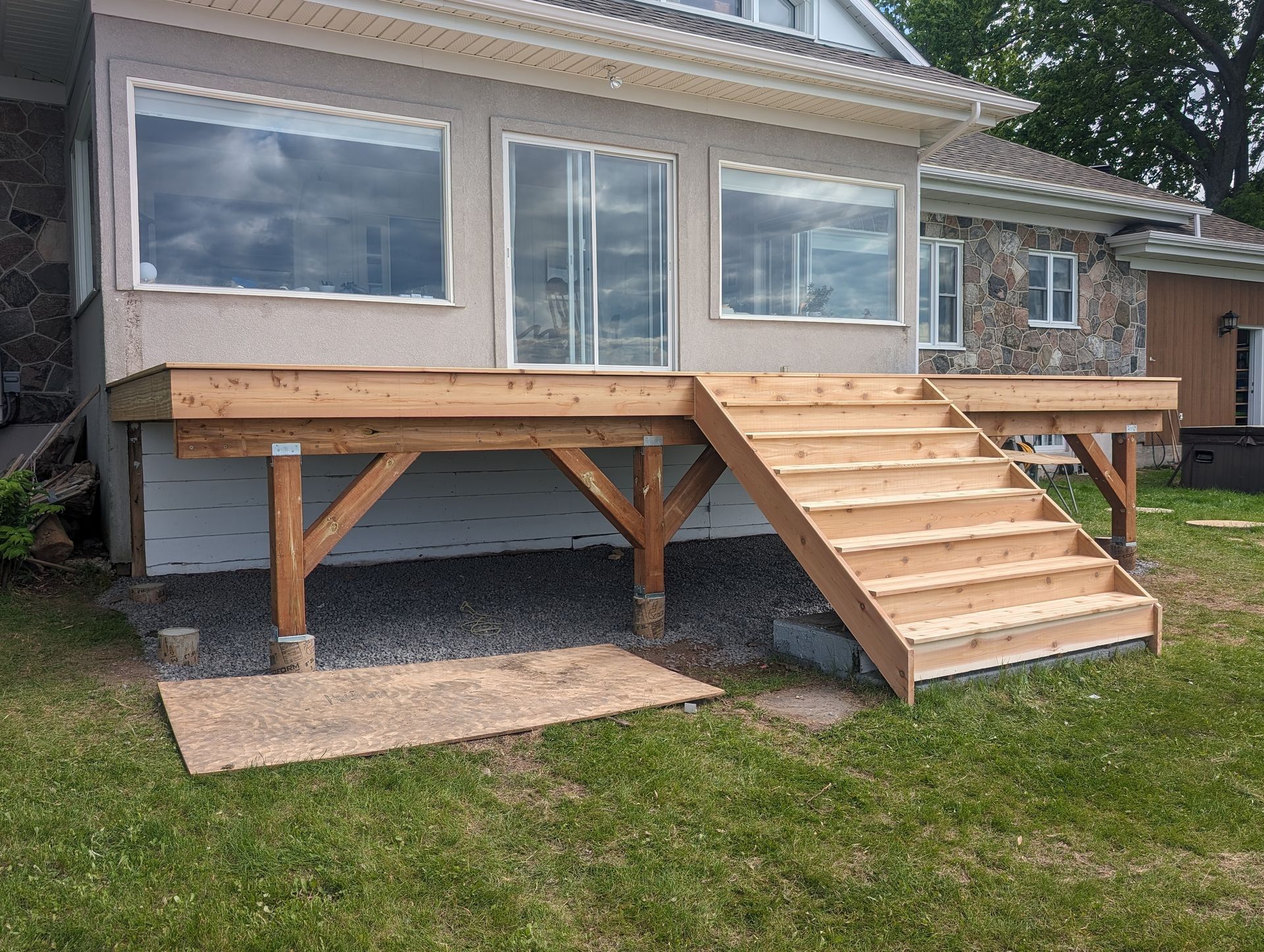 Une terrasse en bois avec des escaliers se trouve devant une maison.