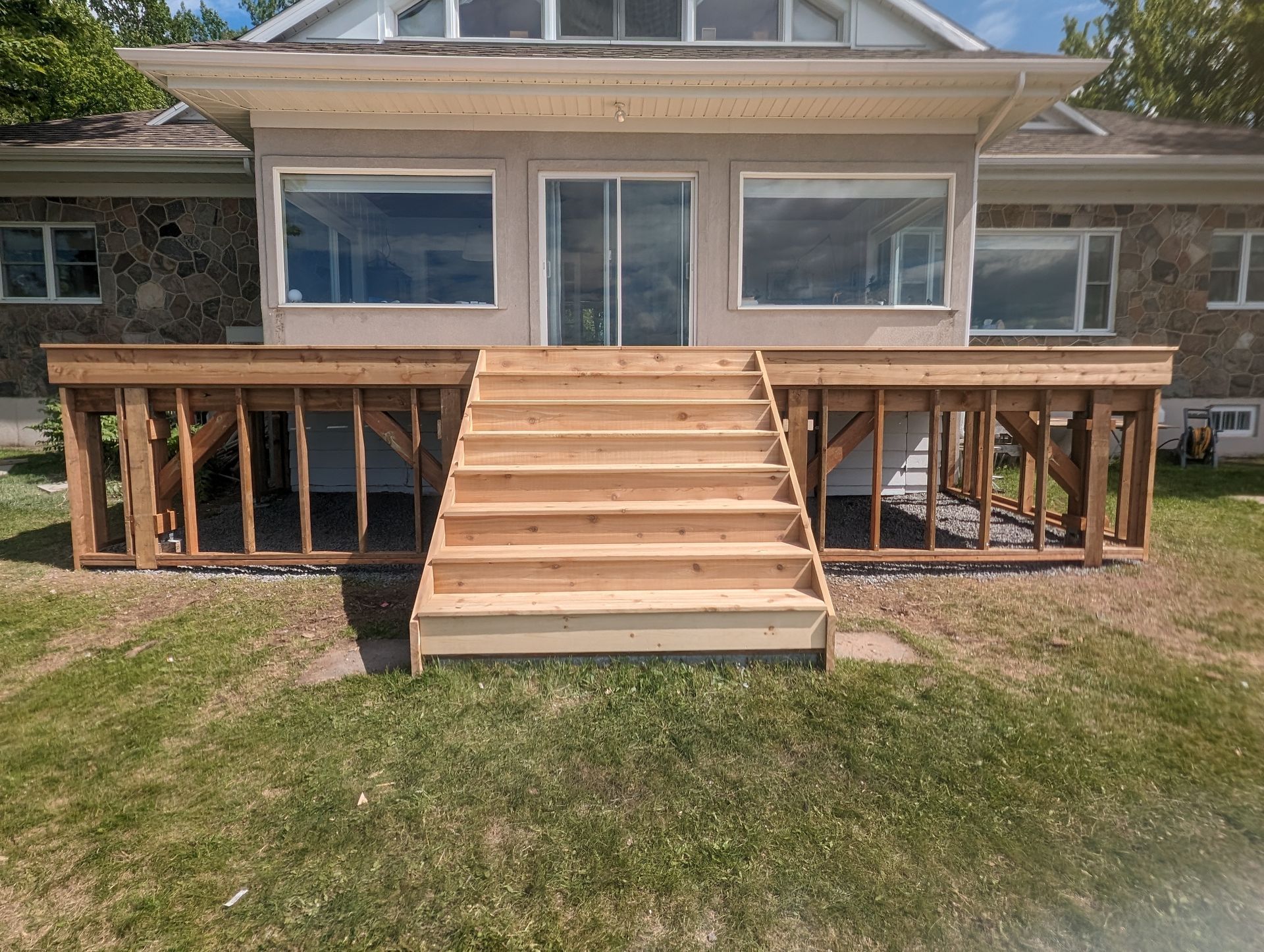 Une terrasse en bois avec des escaliers est en cours de construction devant une maison.