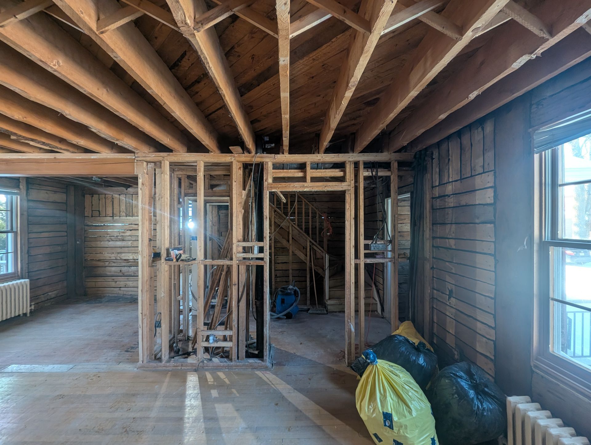 Une pièce vide avec des poutres en bois et un escalier dans une maison en construction.