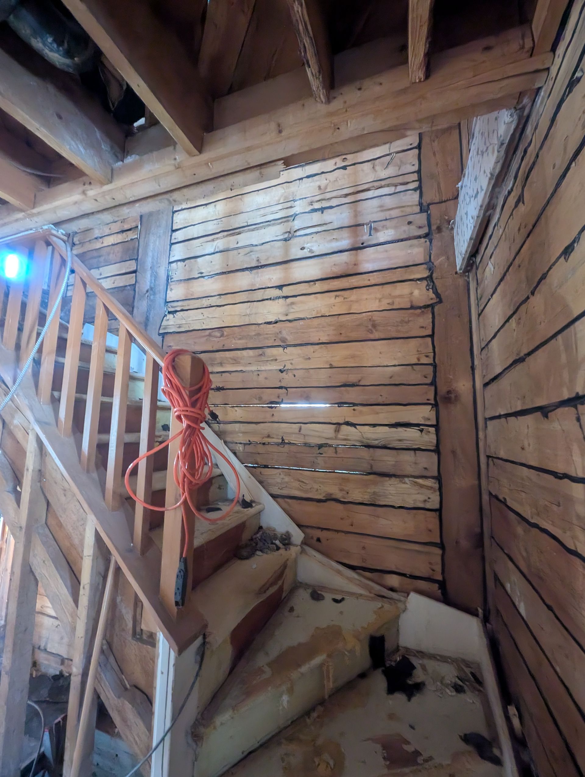 Un escalier en bois avec une corde suspendue à la rampe