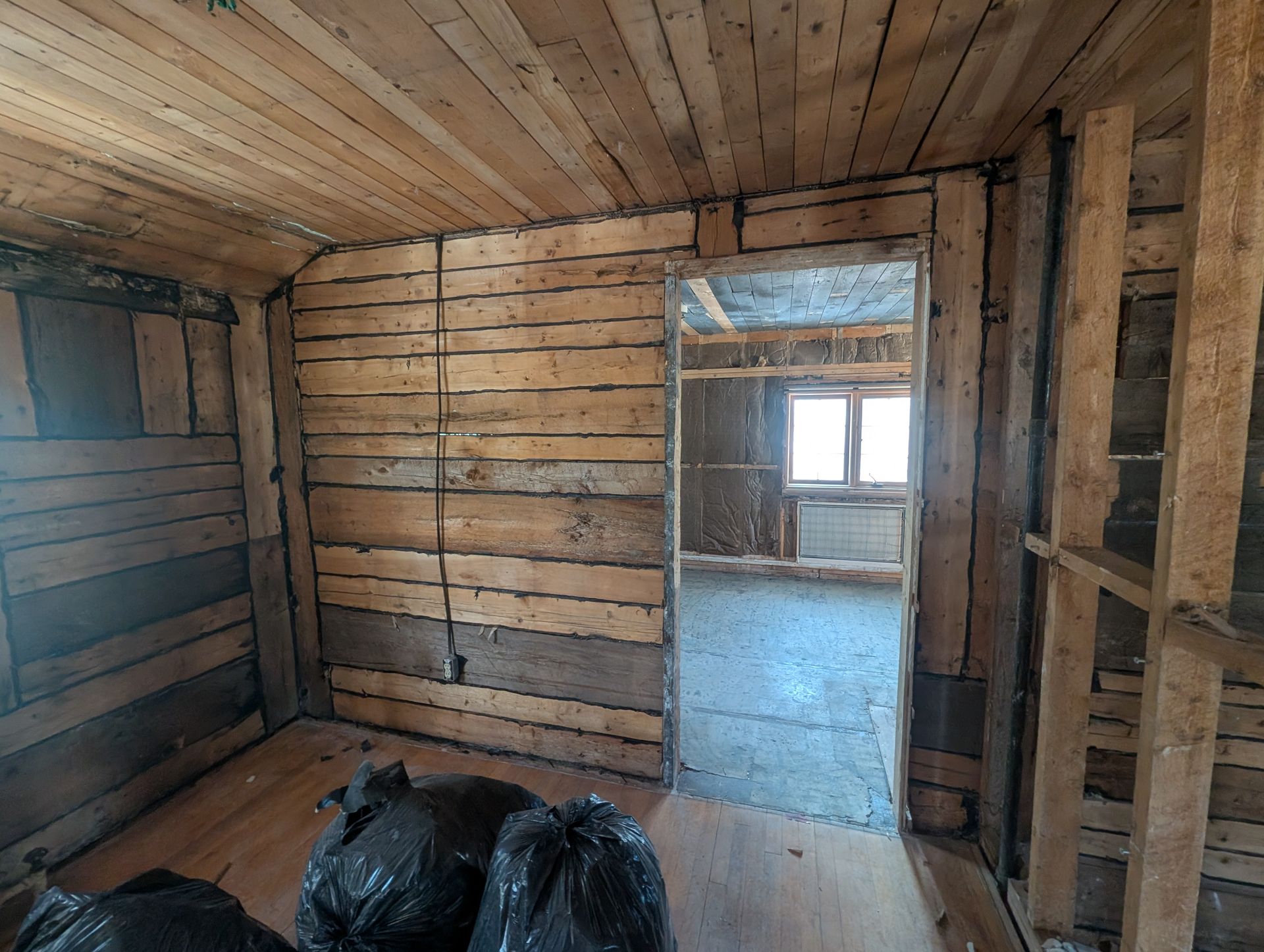 Une pièce avec des murs en bois et une porte menant à une autre pièce.