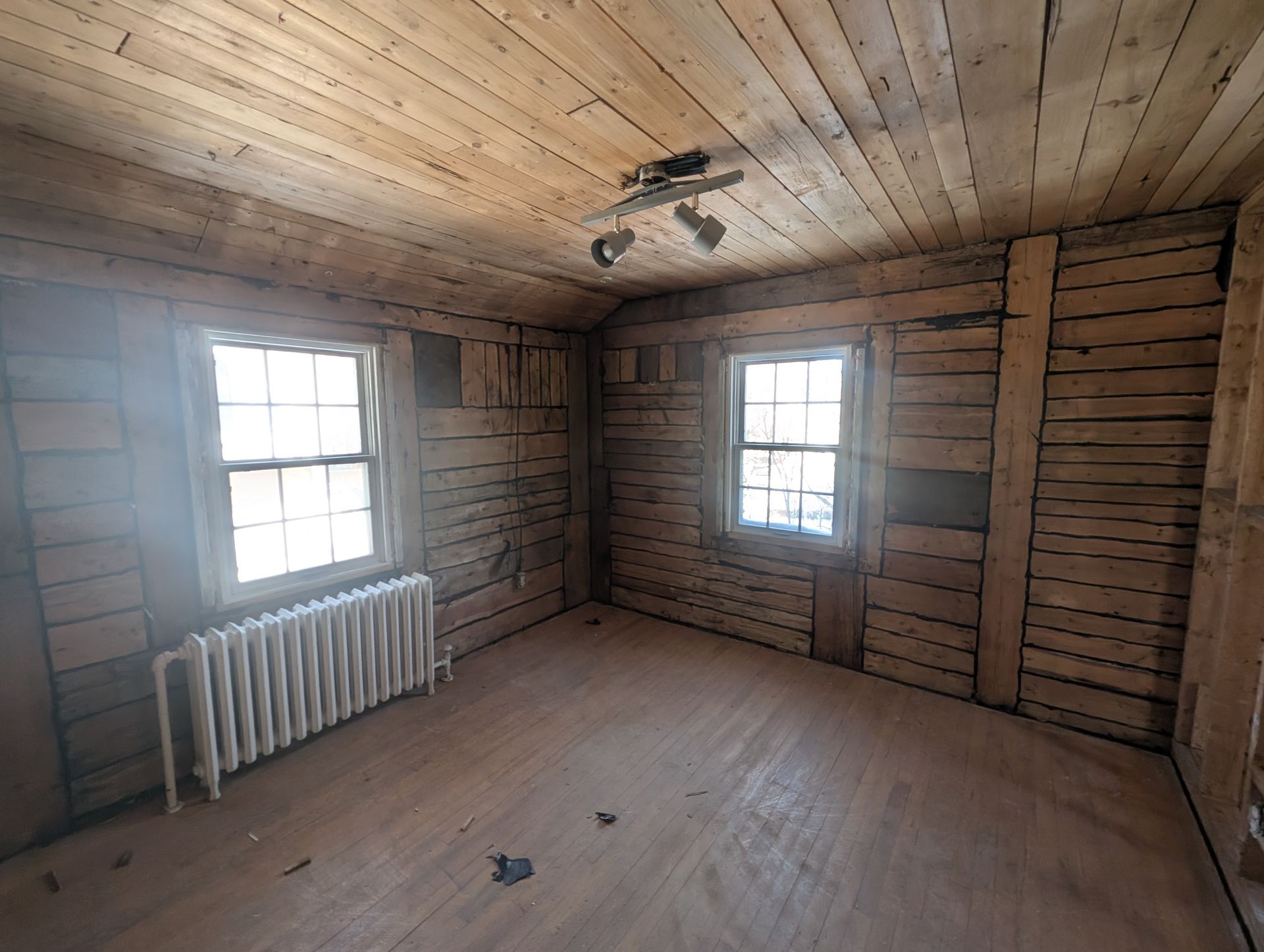 Une pièce vide avec un radiateur et deux fenêtres