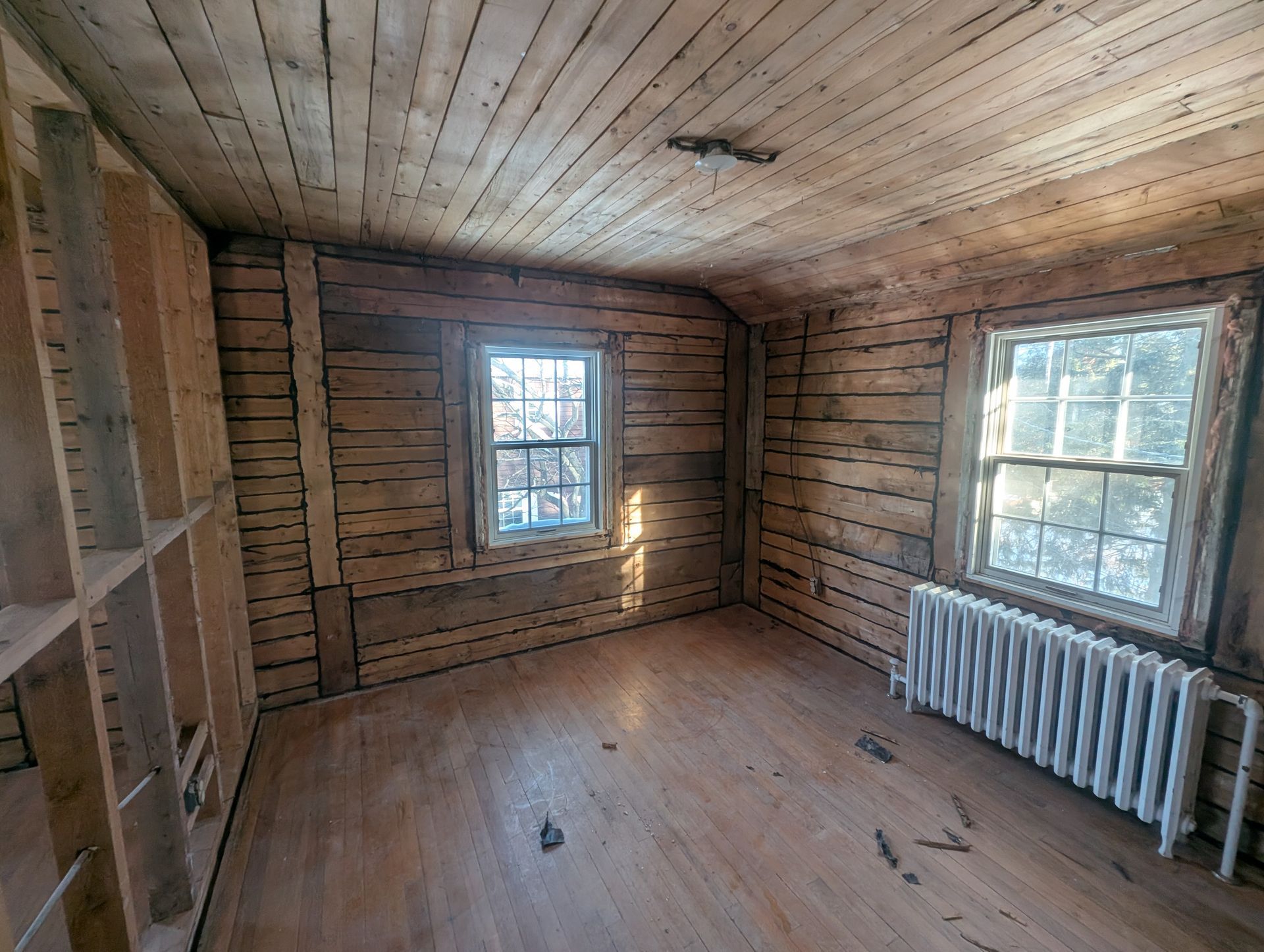 Une pièce vide avec des murs en bois et un radiateur.
