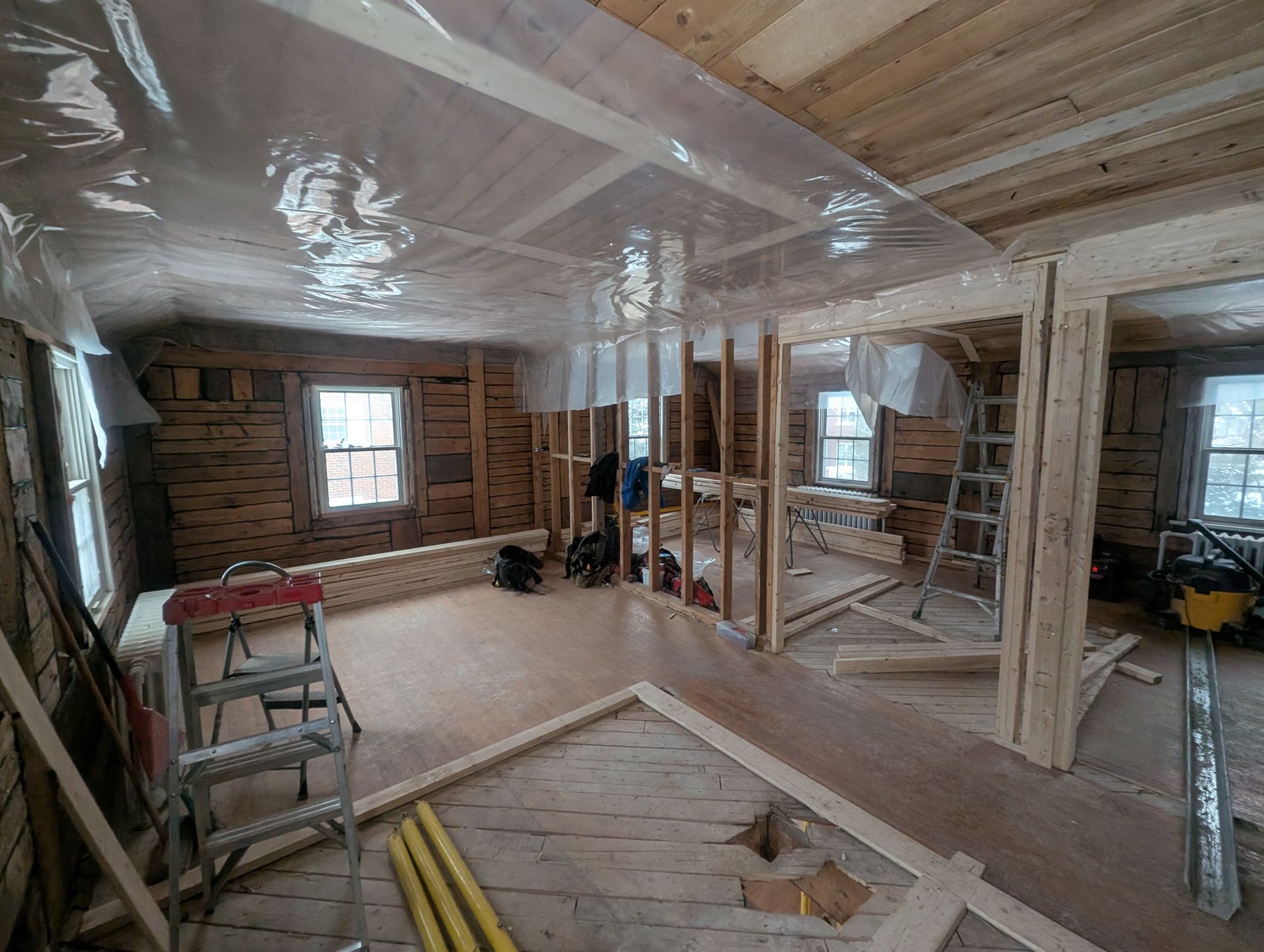 Une pièce en cours de construction avec beaucoup de bois et de plastique recouvrant le plafond.