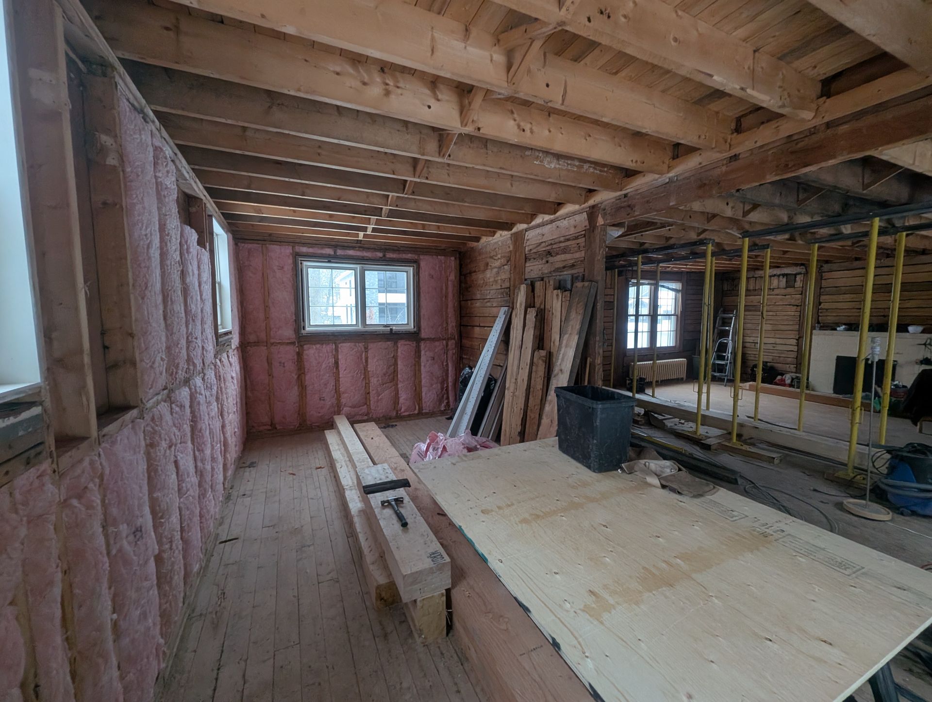 Une pièce dans une maison en construction avec poutres en bois et isolation.