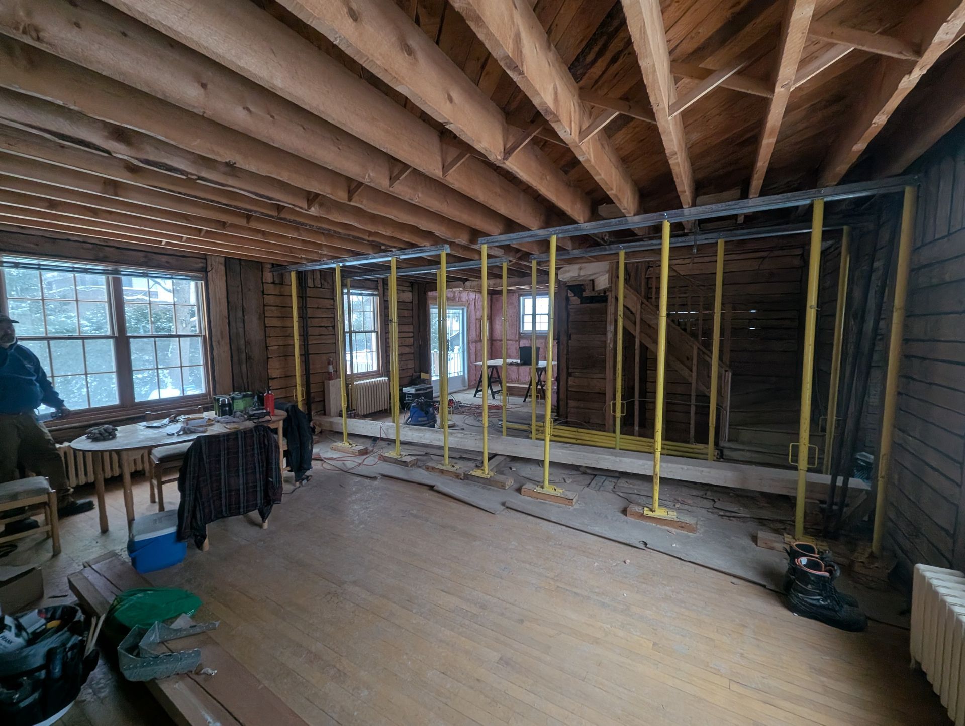Une grande pièce avec un plancher en bois et un plafond en bois est en cours de rénovation.