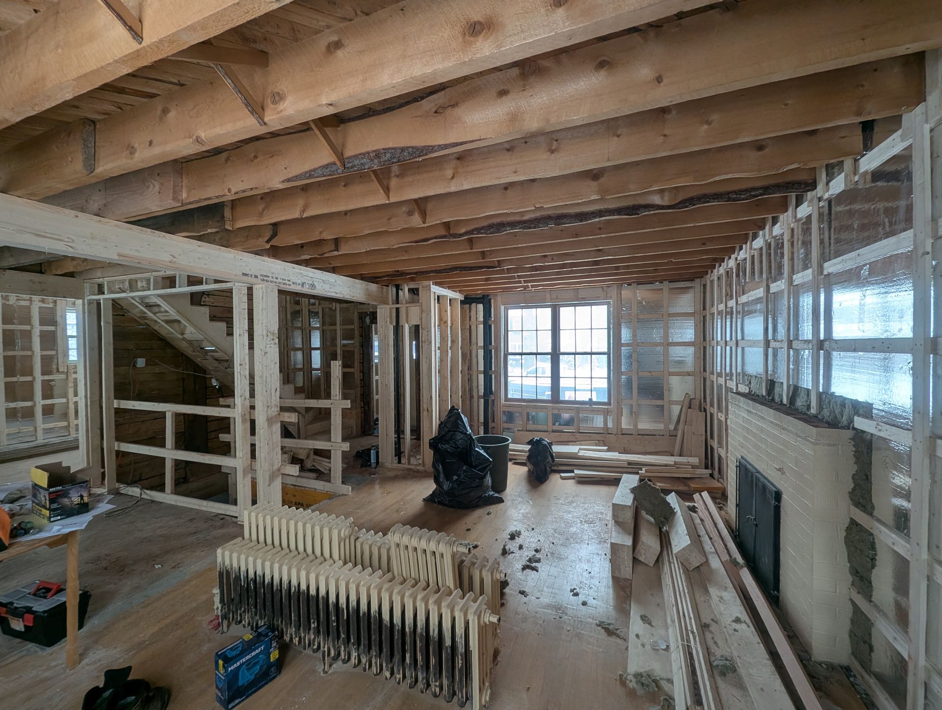L'intérieur d'une maison en construction avec des poutres en bois et une cheminée.