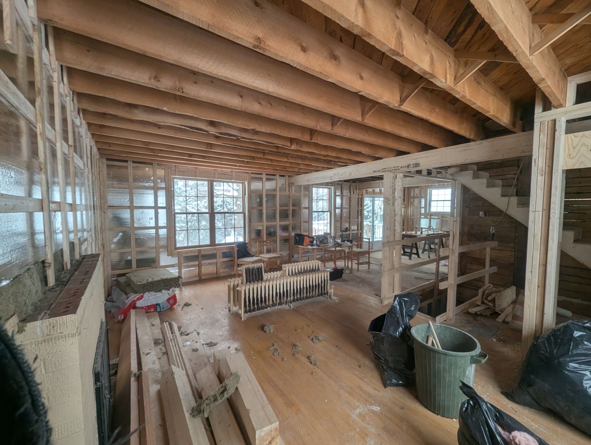 Une grande pièce avec poutres en bois et escalier en construction.