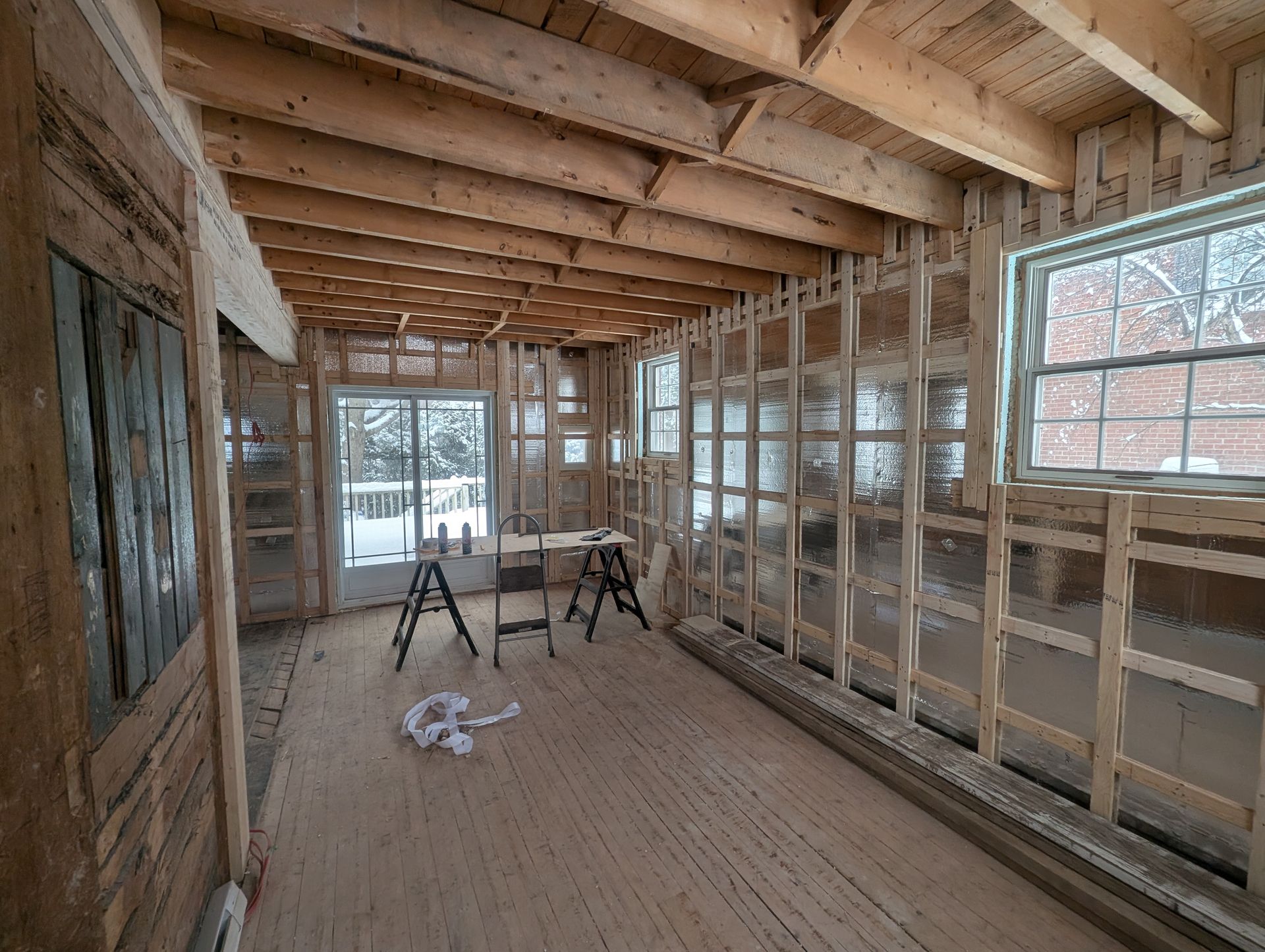 Une pièce en construction avec poutres et fenêtres en bois.