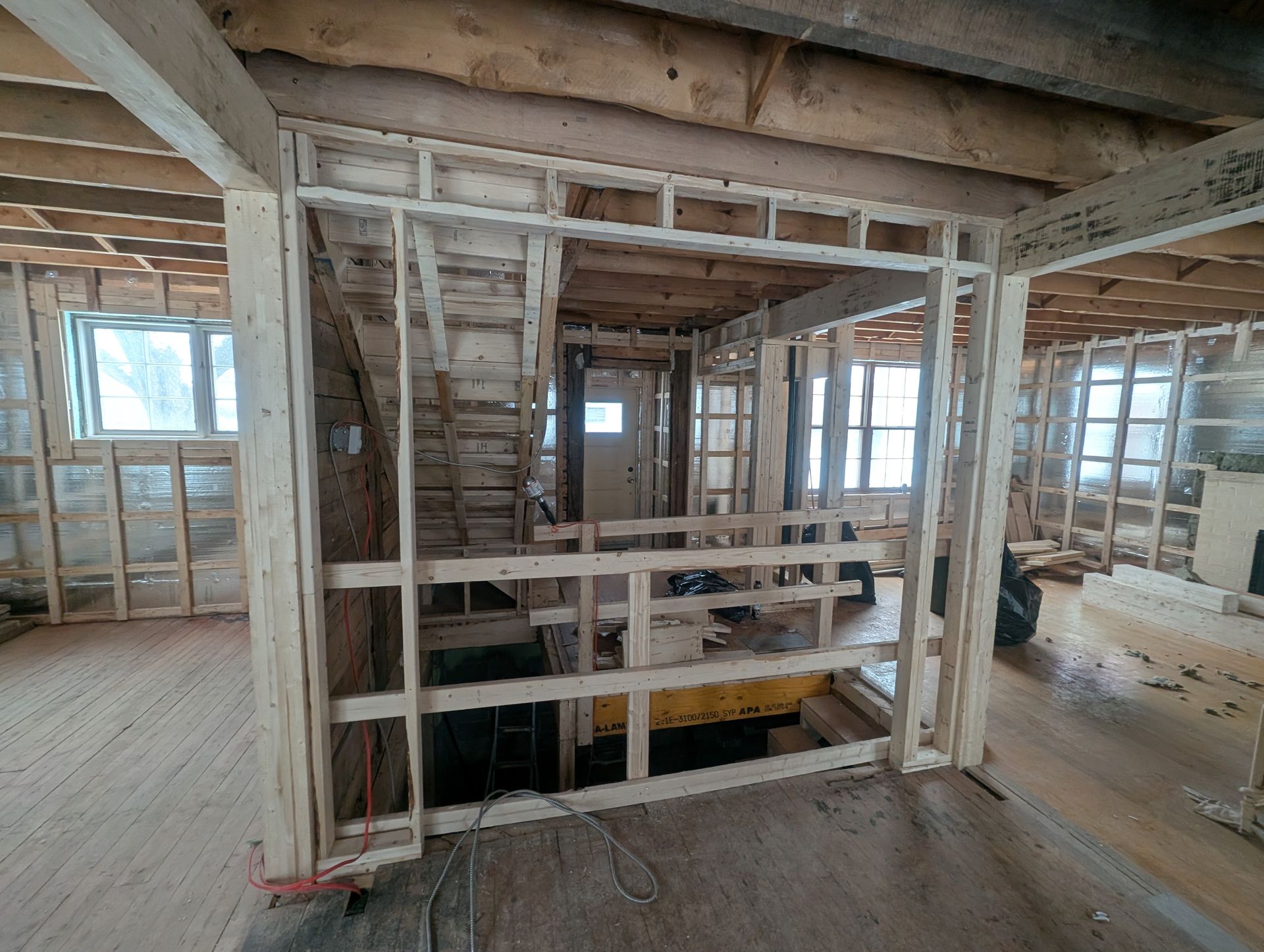 Une maison est en construction avec des poutres en bois et un escalier.