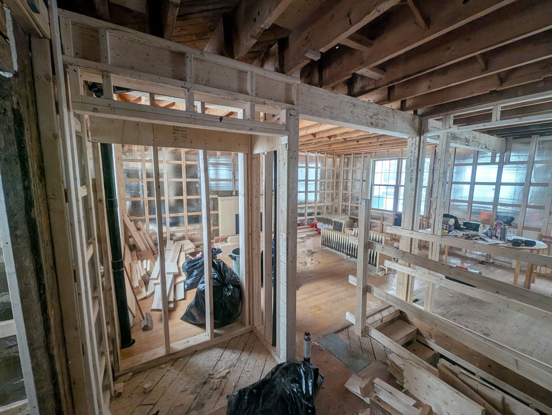 Une maison est en construction avec des poutres en bois et beaucoup de fenêtres.