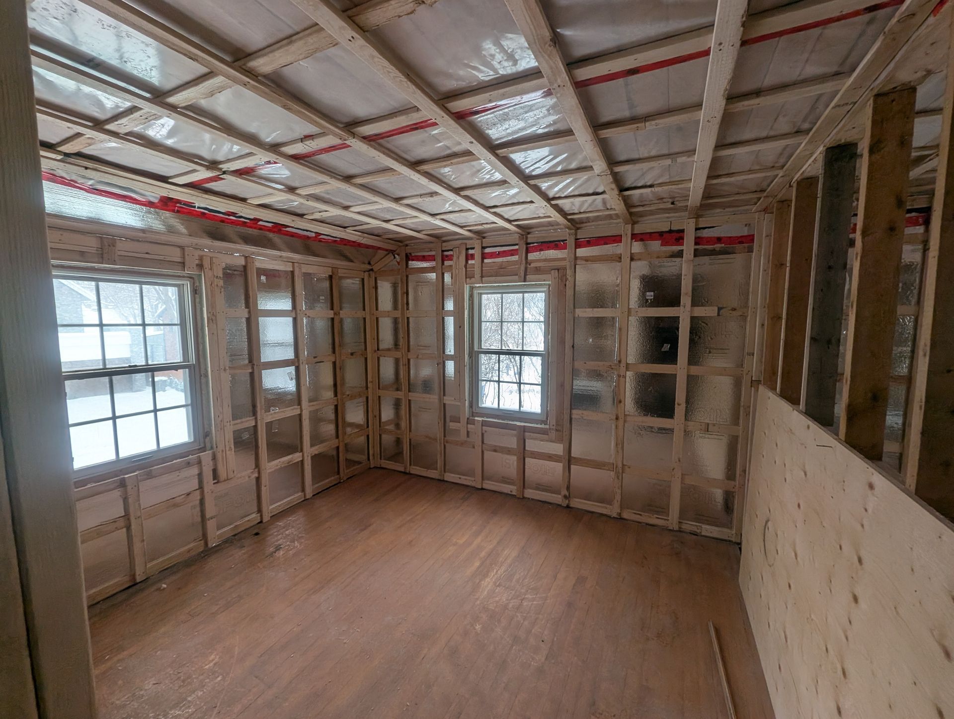 Une pièce vide avec des murs en bois et un plafond dans une maison en construction.