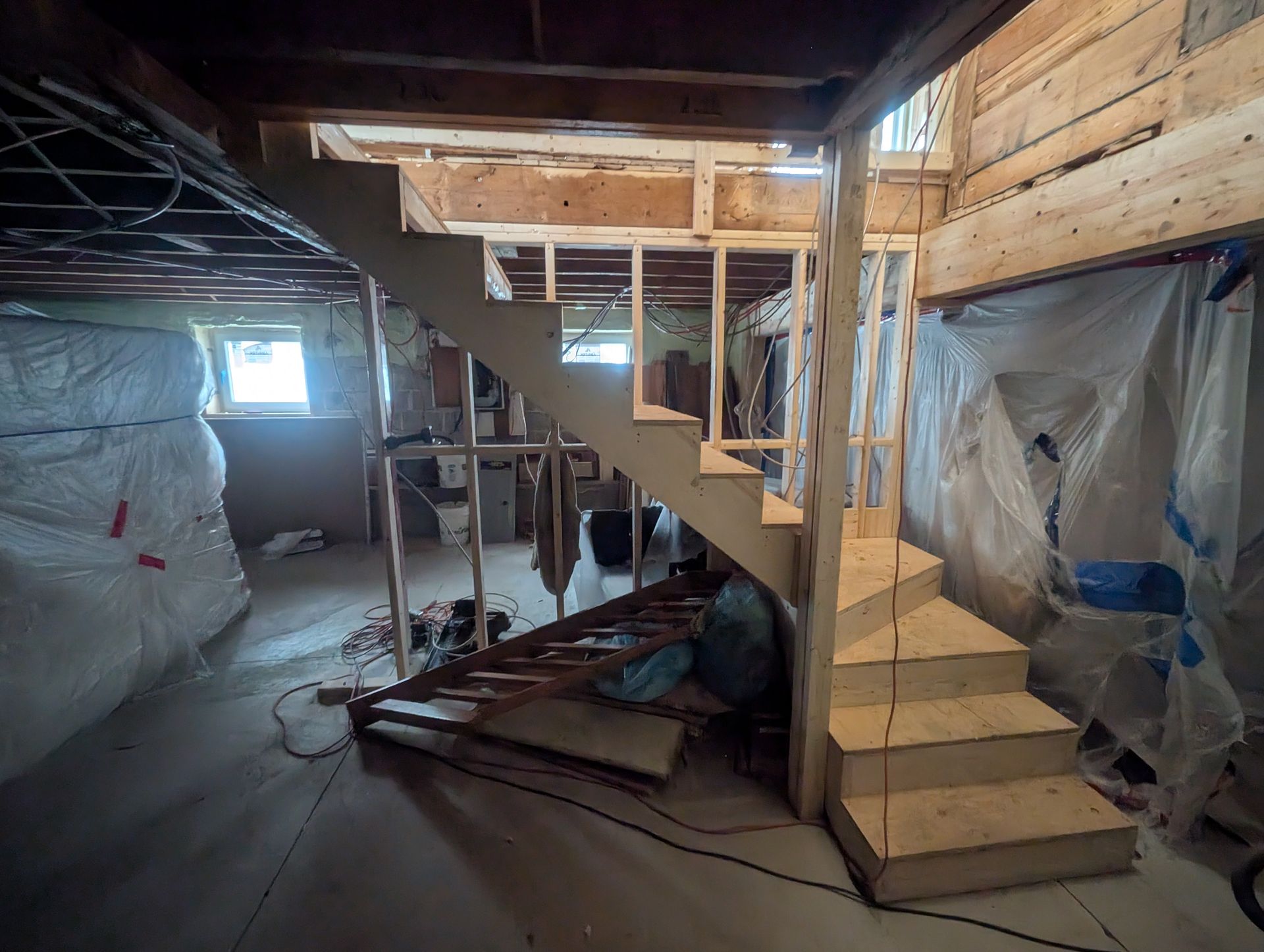 Un escalier en bois est en cours de construction dans un sous-sol.