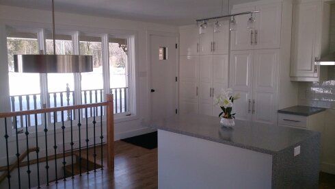 Une cuisine avec des armoires blanches, des comptoirs en granit et un grand îlot.