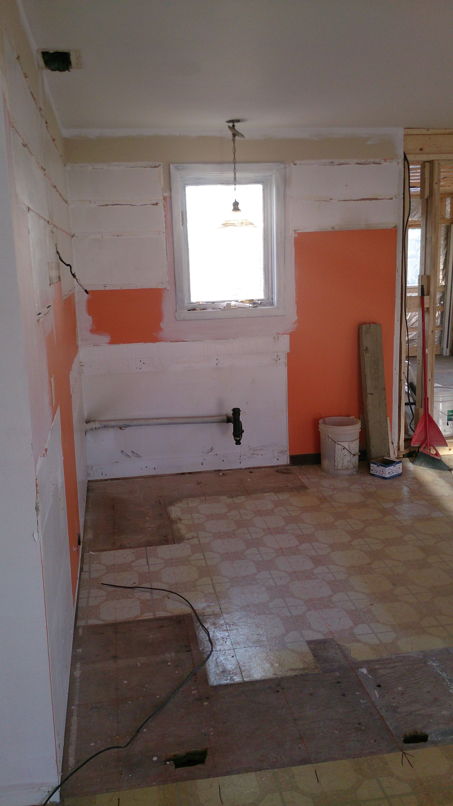 Une cuisine vide avec des murs orange et une fenêtre.