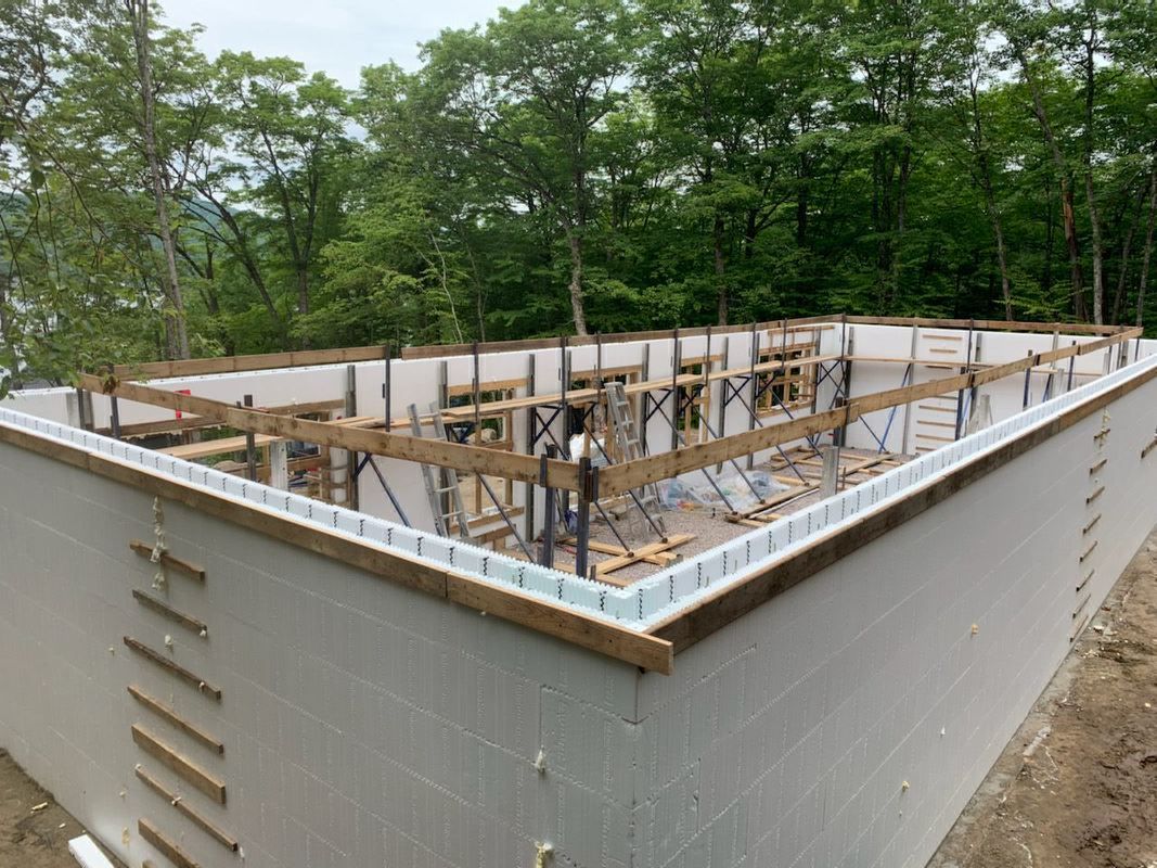 Un grand bâtiment blanc est en construction au milieu d'une forêt.