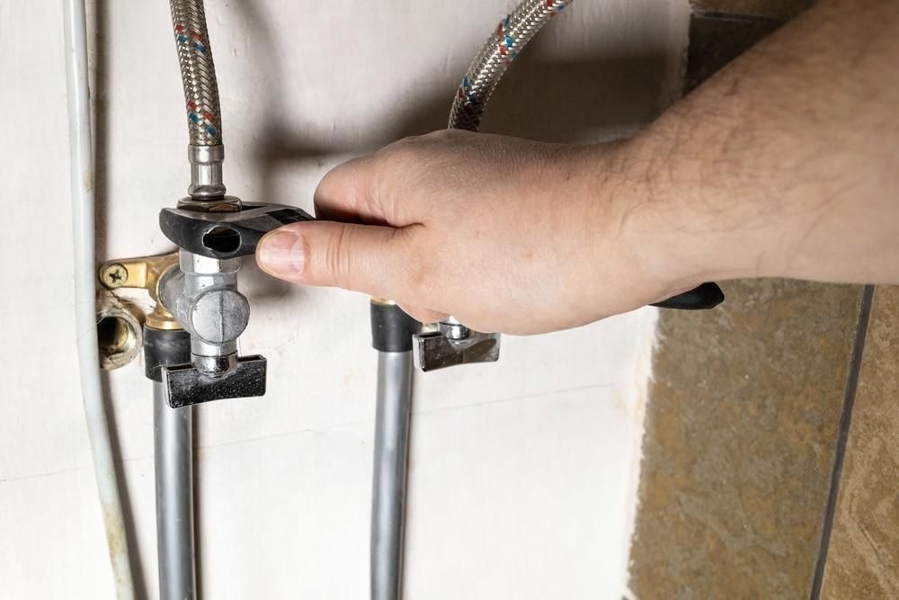 A person is fixing a faucet with a wrench.