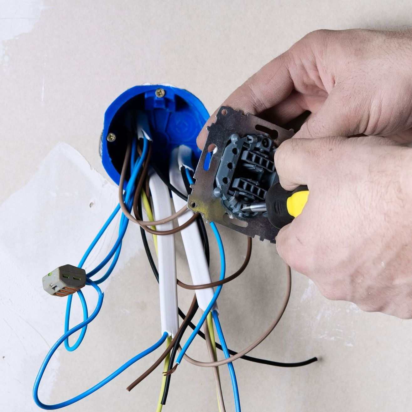 A person is fixing a light switch with a pair of pliers