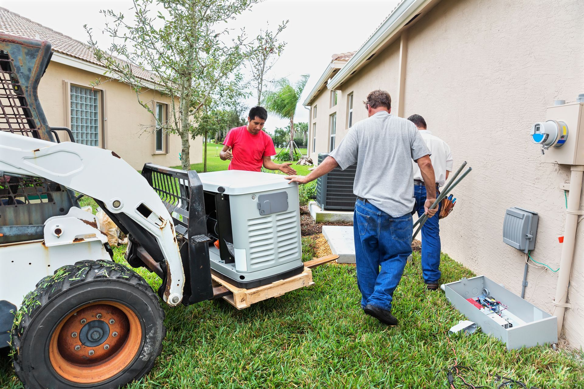 A group of men are working on a generator outside of a house.