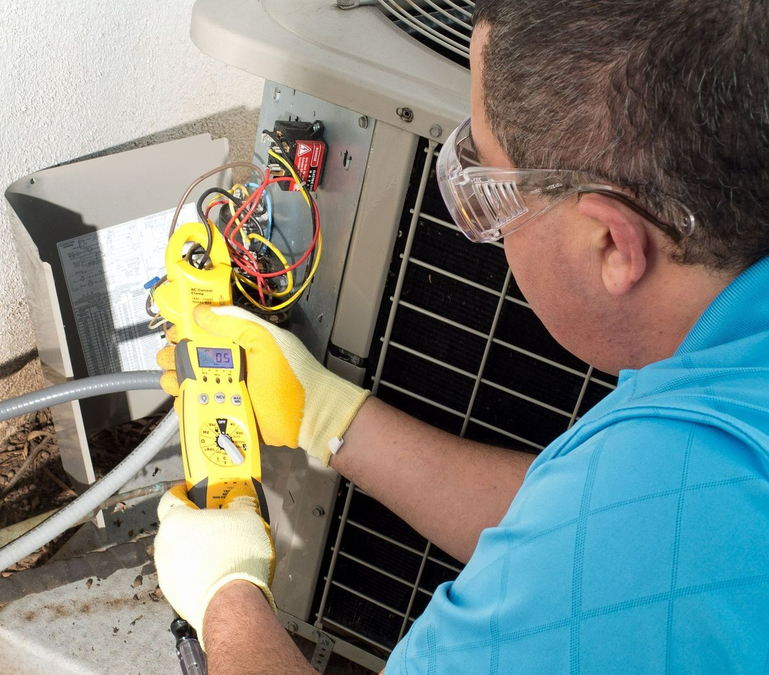 A man in a blue shirt is working on an air conditioner
