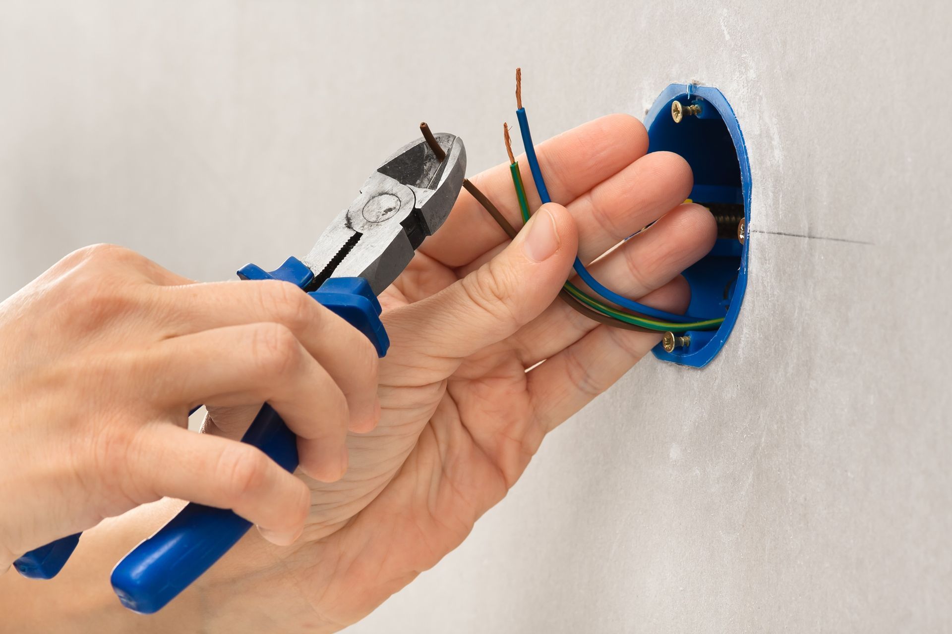 A person is cutting a wire with a pair of pliers.