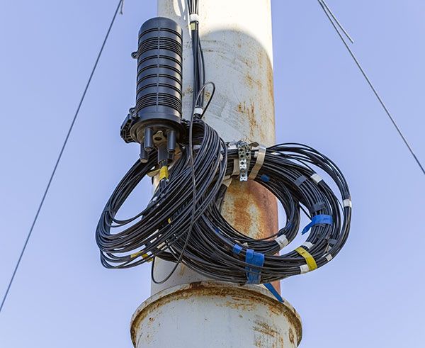 A bunch of wires are hanging from a pole.