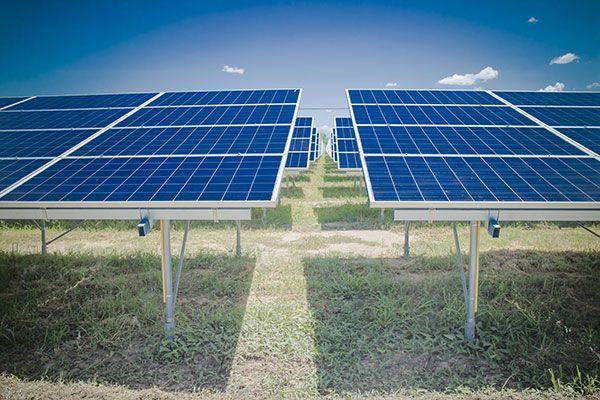 A row of solar panels in a field with a blue sky in the background.