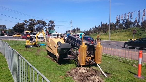 A tractor is digging a hole in the grass next to a road.