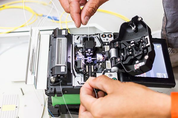 A person is working on a fiber optic splicer.