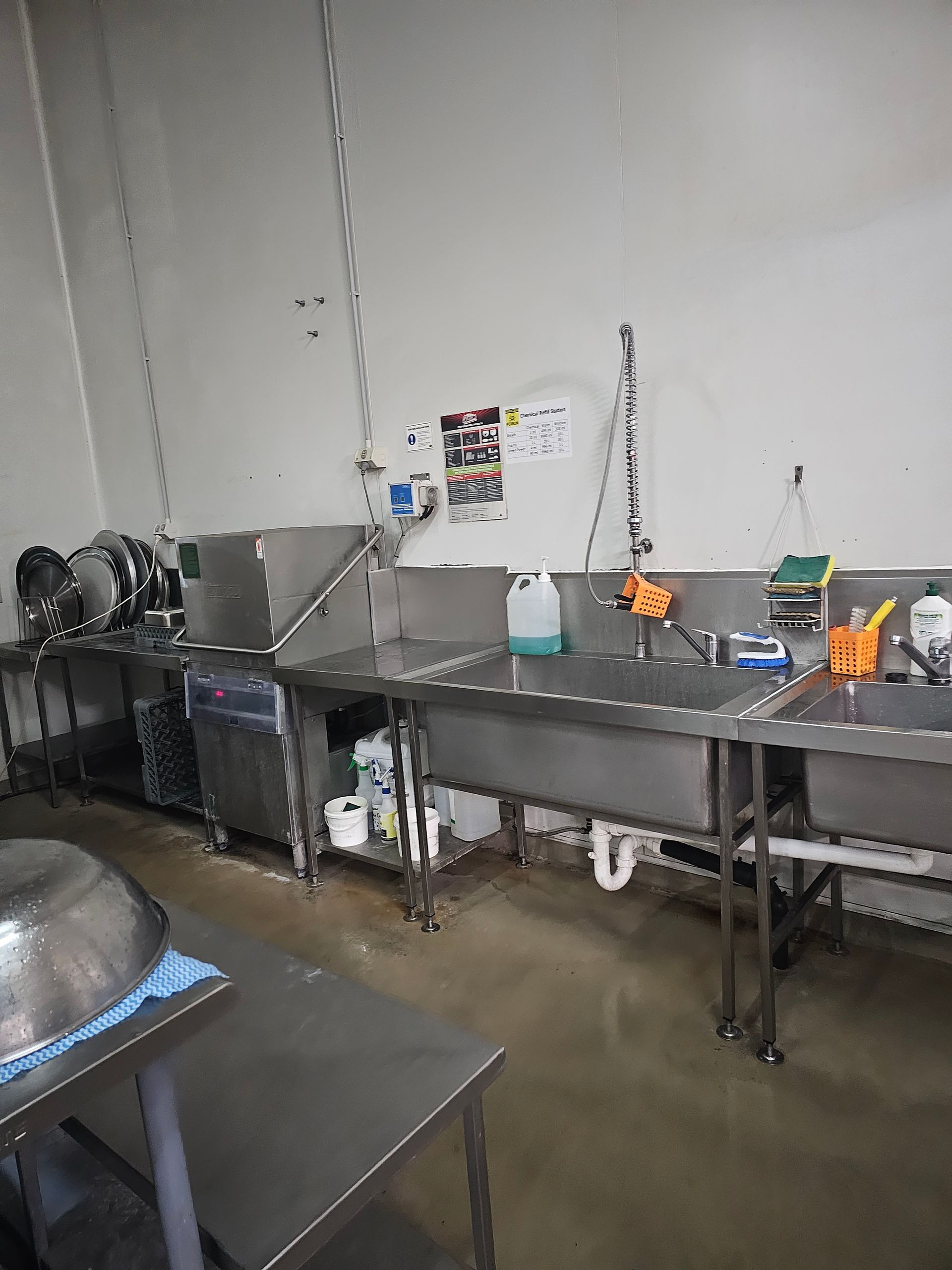 A row of stainless steel sinks in a kitchen.